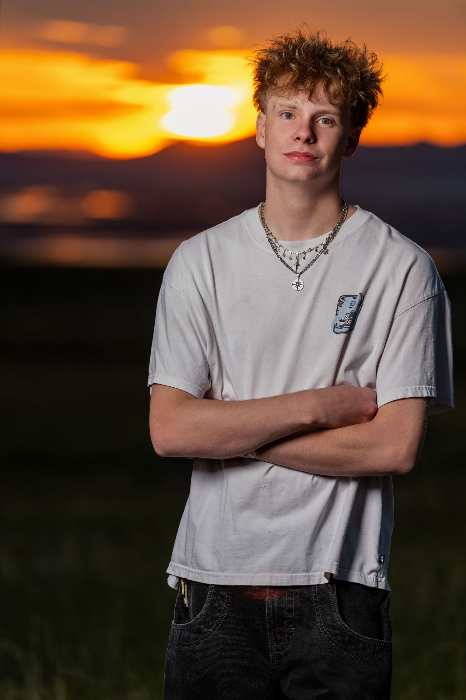 Dramatic sunset senior portrait of teenage boy with glowing orange sky background in Utah