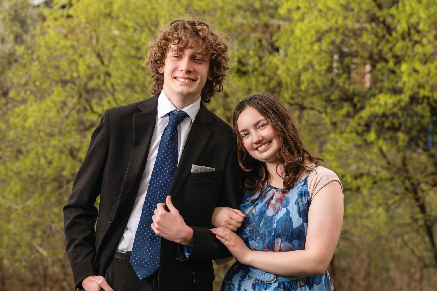 High school prom couple portrait outdoors with formal attire and natural spring background