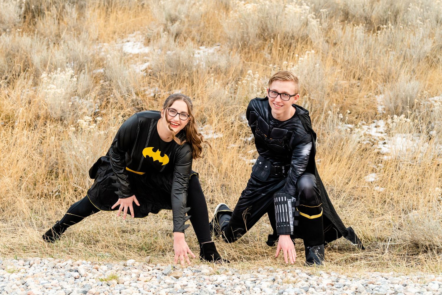 Two seniors in Batman themed outfits with playful pose in natural setting for Woods Cross Sadie Hawkins dance