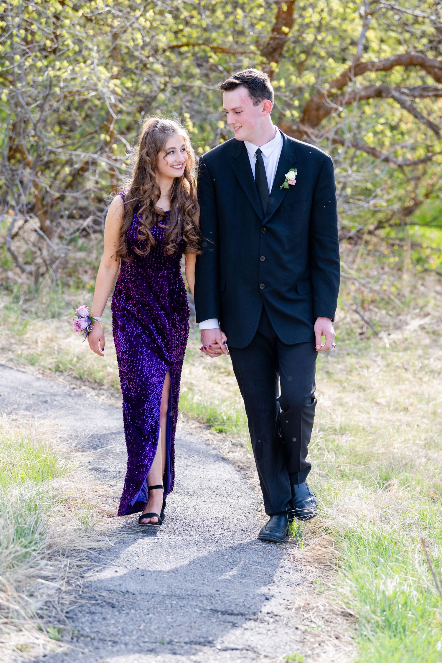 Couple walking together on path outdoors in formal attire with soft light