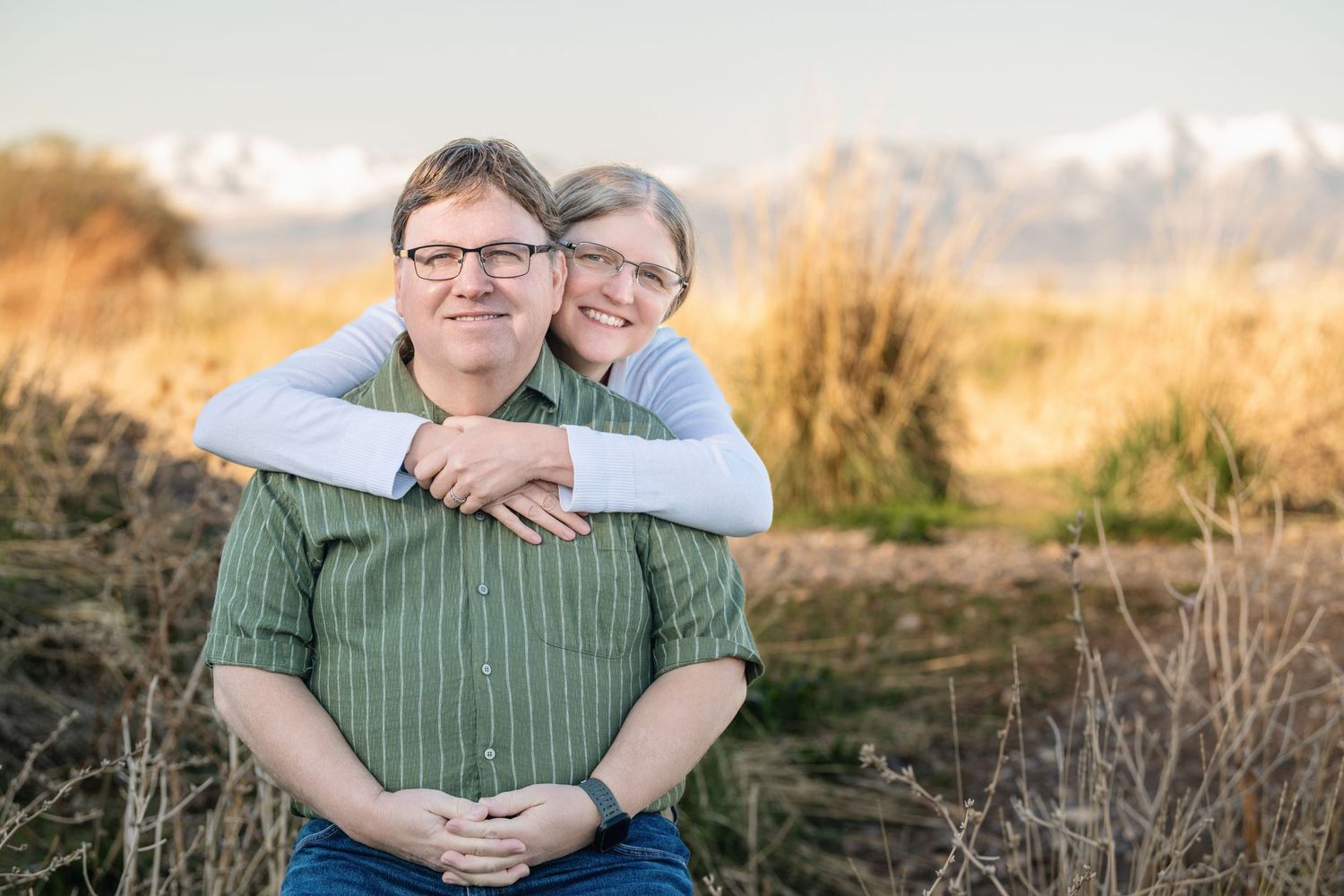Outdoor family portrait of smiling couple embracing with mountain landscape in the background