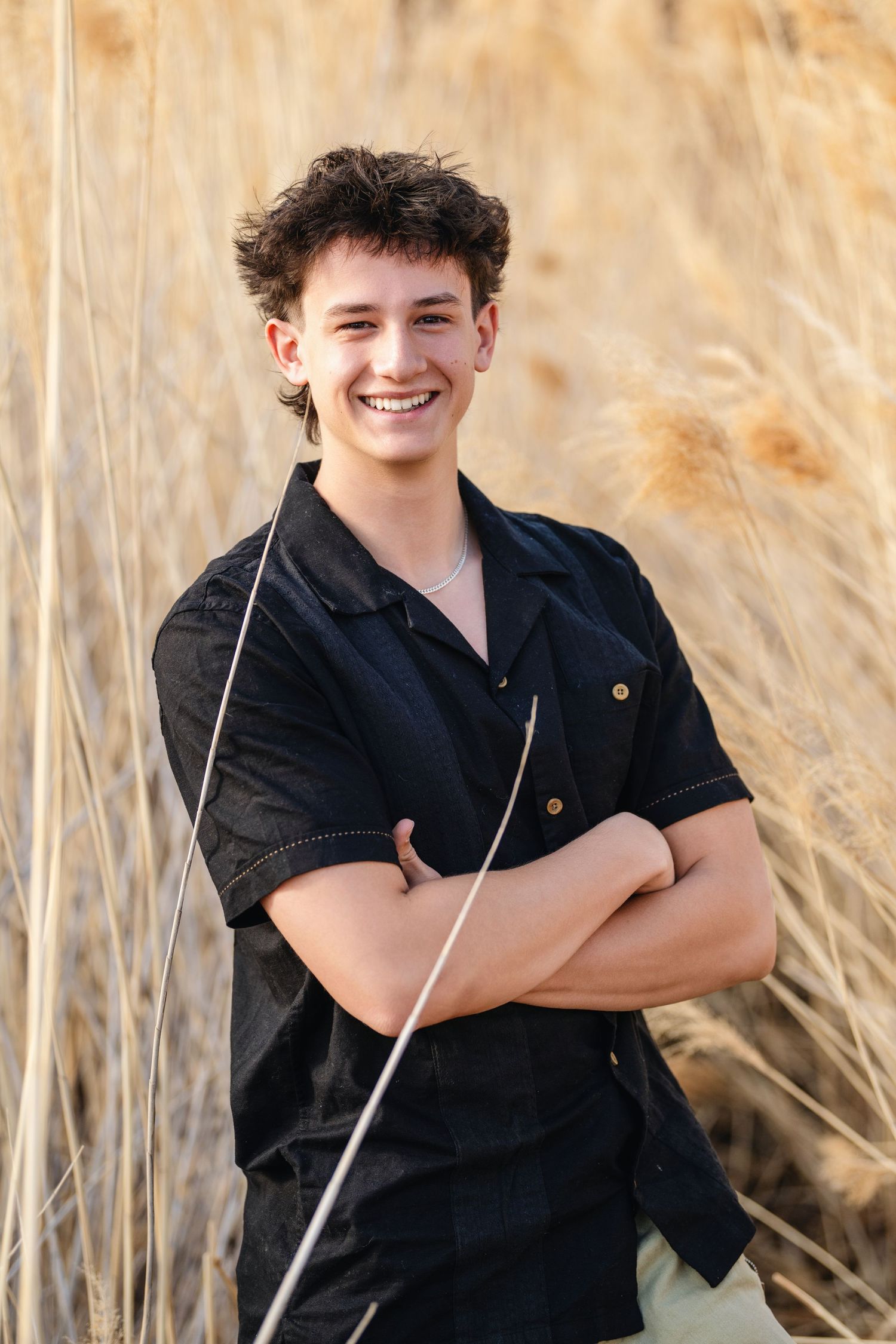 Male senior portrait with casual black outfit standing in tall grass during Utah senior session