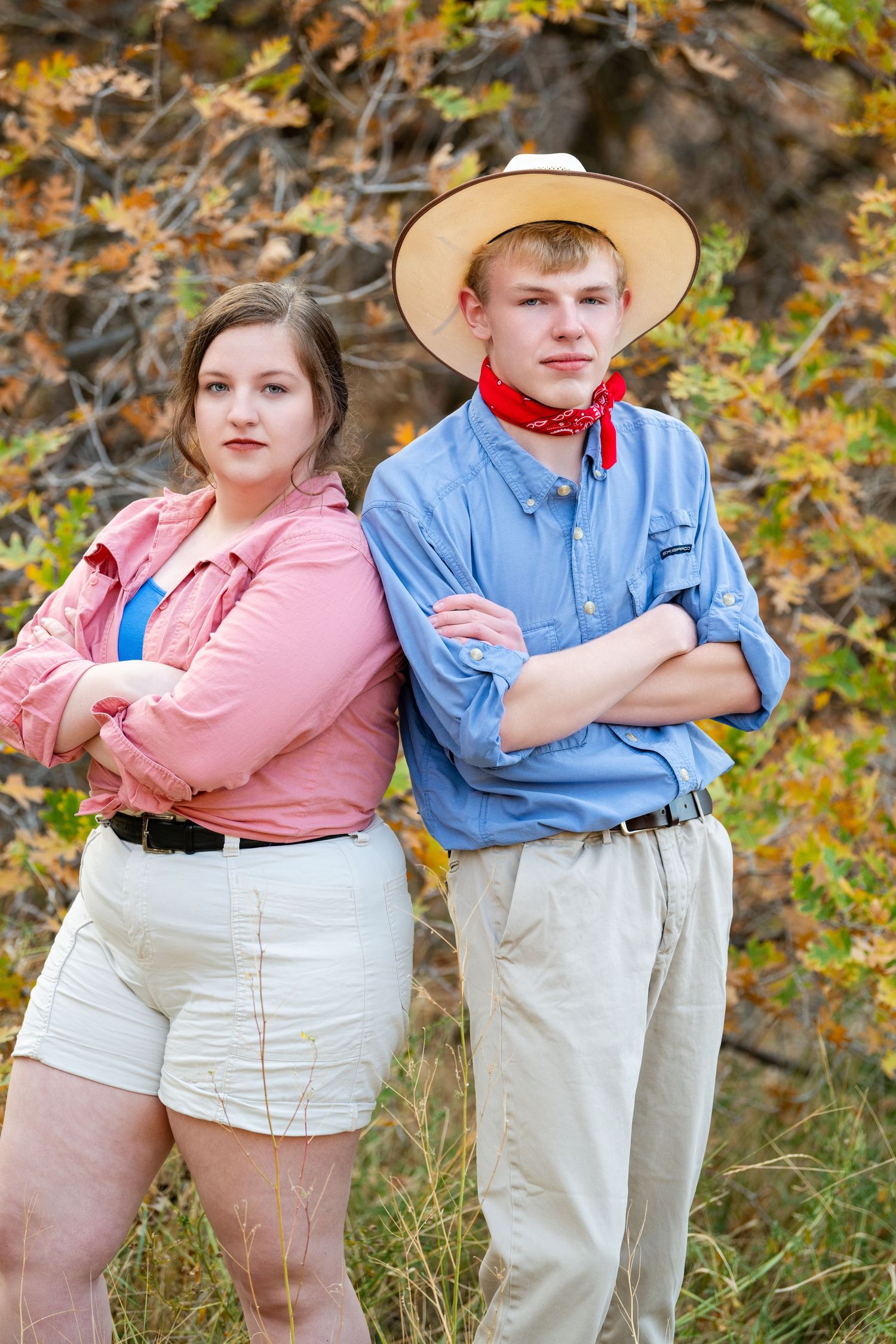 Two teens in Jurassic Park themed outfits for Sadie Hawkins dance standing back to back with confident poses outdoors