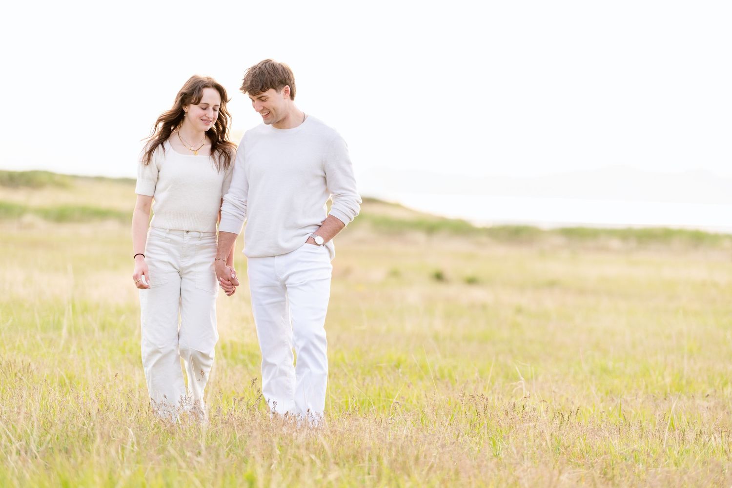 Casual engagement couple walking through grassy field during outdoor Utah photography session