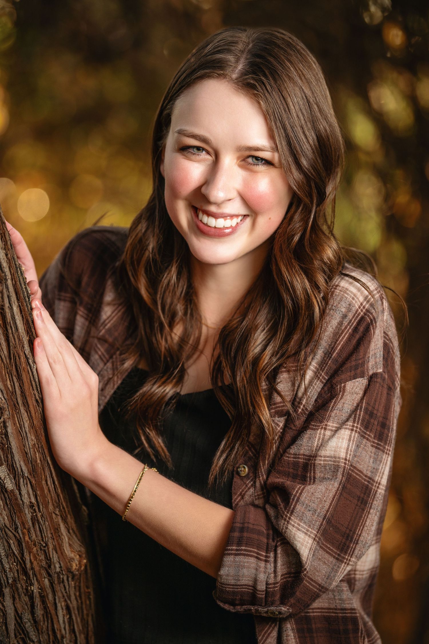 Smiling girl portrait beside tree during warm autumn outdoor photography session