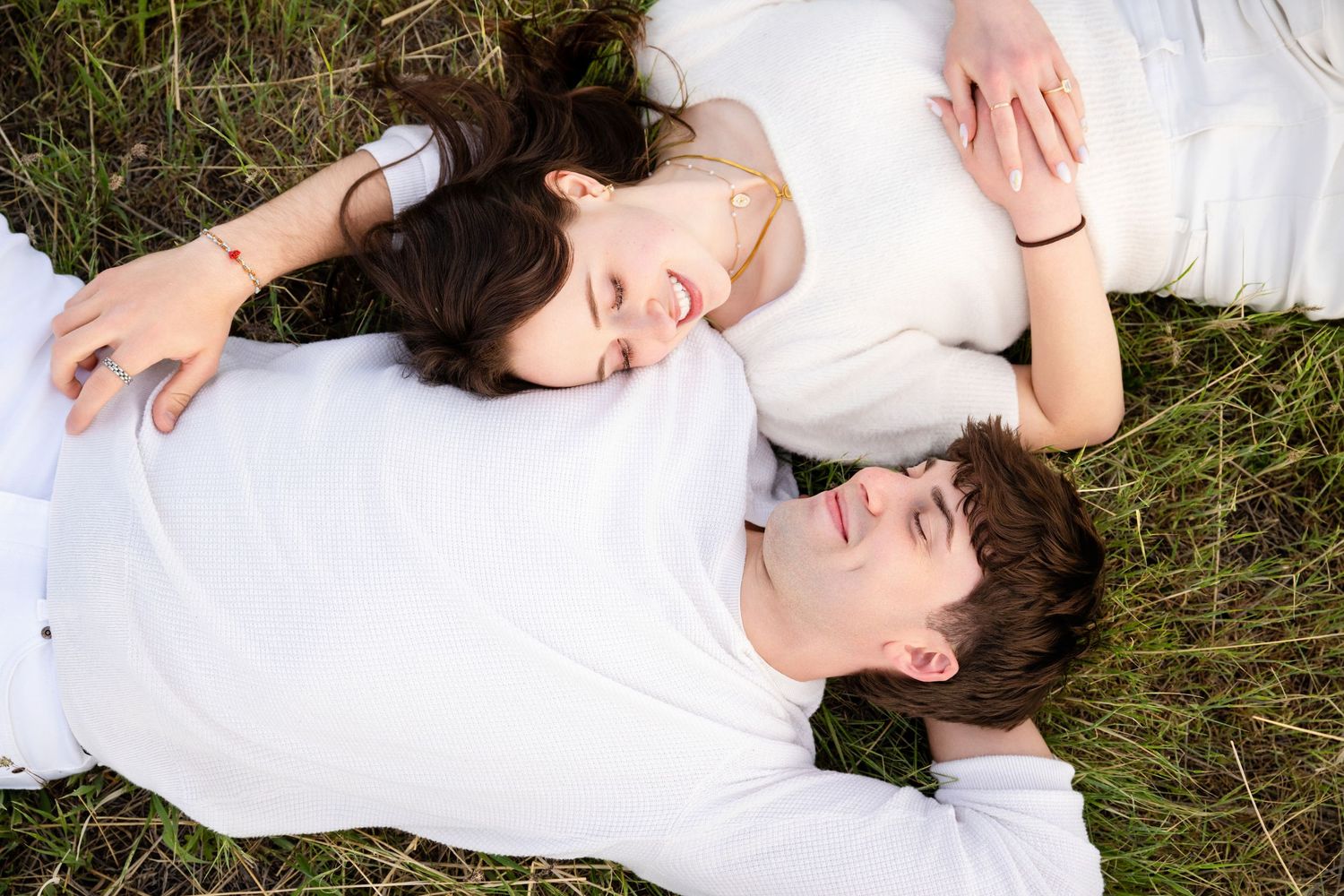 Romantic engagement couple lying together in grassy field during natural light Utah session