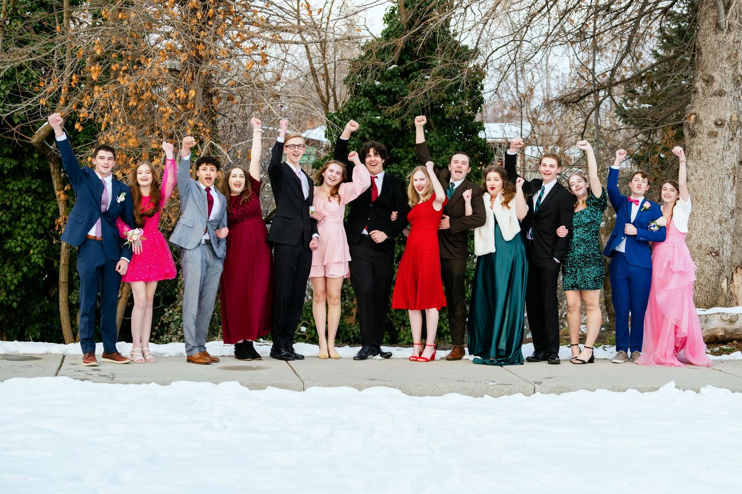 Large group of teens in formal attire celebrating Woods Cross Sweethearts dance together outdoors in winter setting