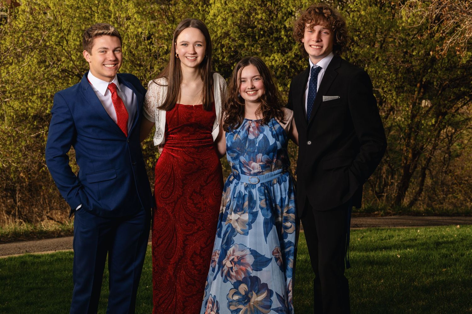 Group prom photo featuring high school students in formal dresses and suits during outdoor prom session