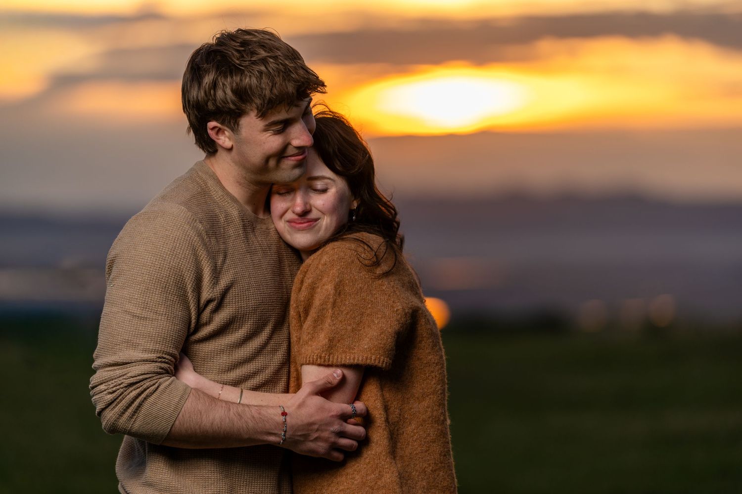 Romantic Utah engagement photo of couple cuddling outdoors at sunset with warm golden light