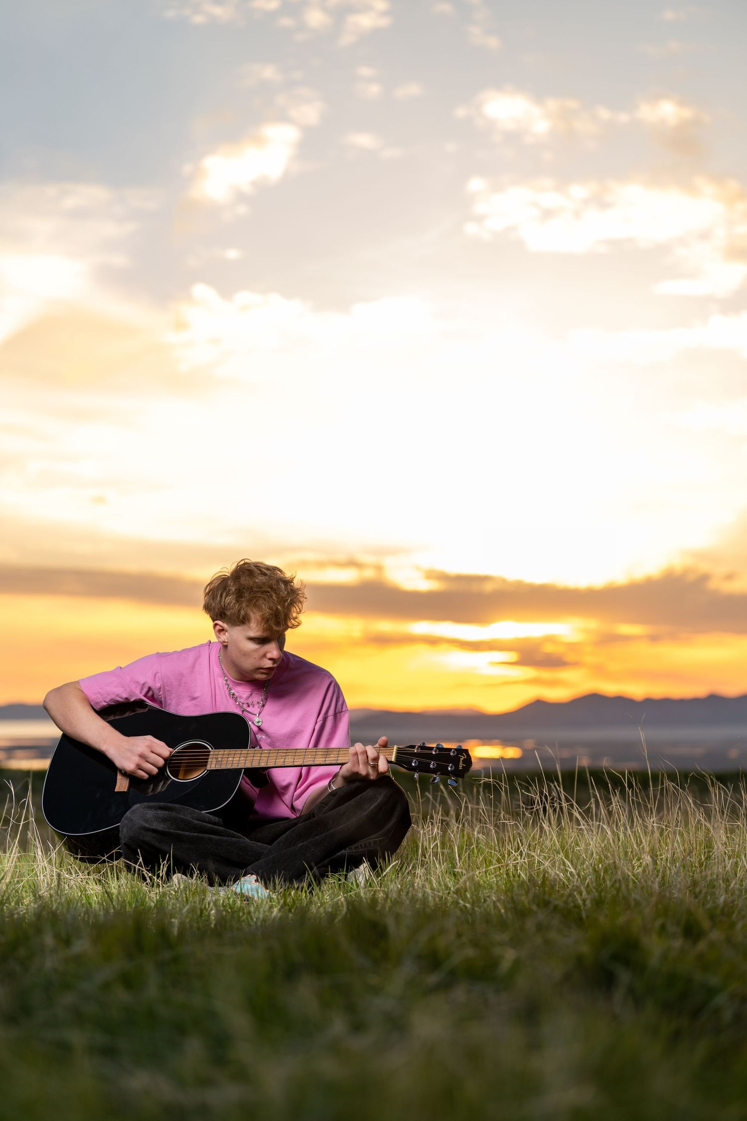 Senior guy playing guitar at sunset during outdoor Utah Class of 2026 photography session