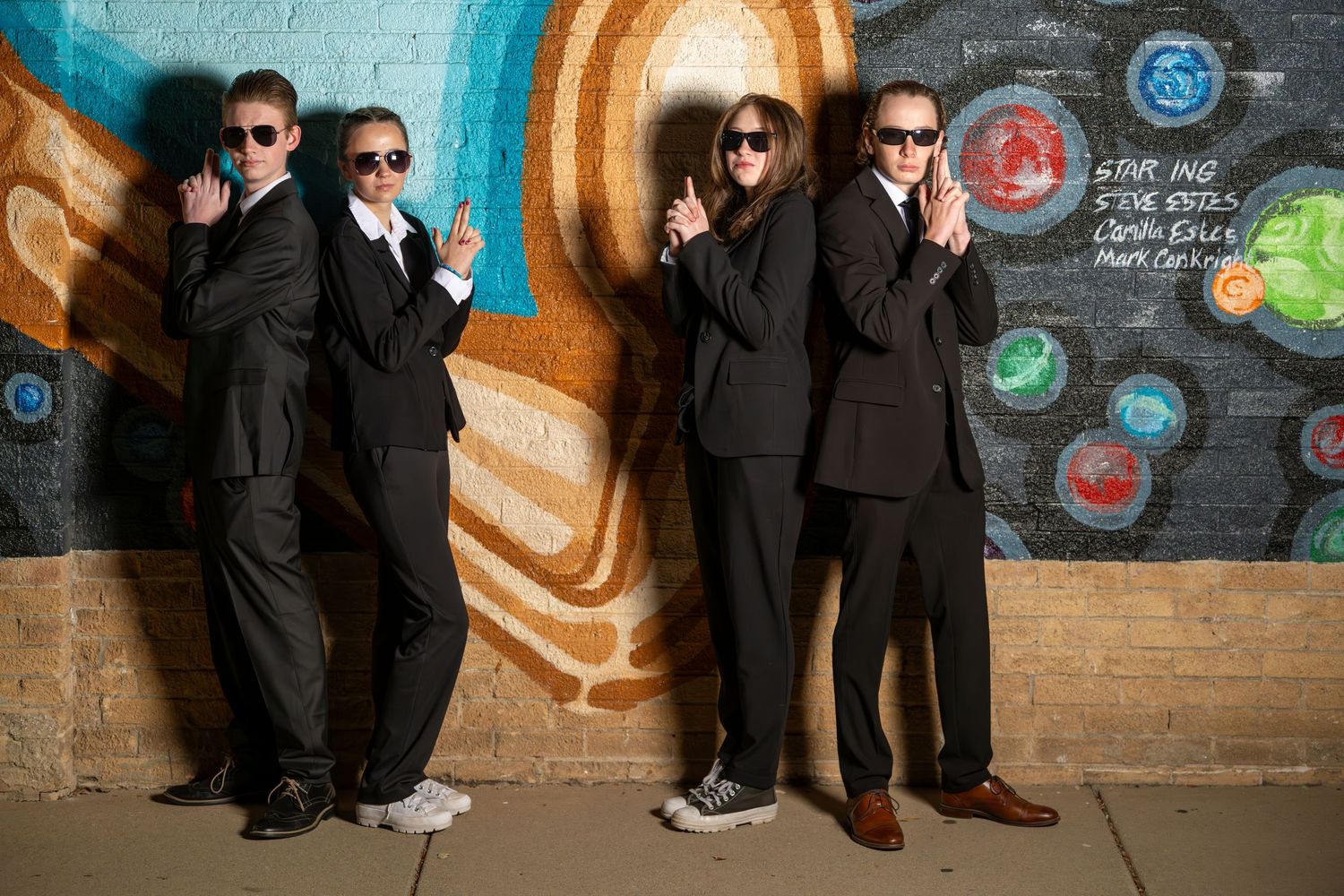 Group Sadie Hawkins Woods Cross High School dance portrait with students in suits posing in front of colorful mural wall