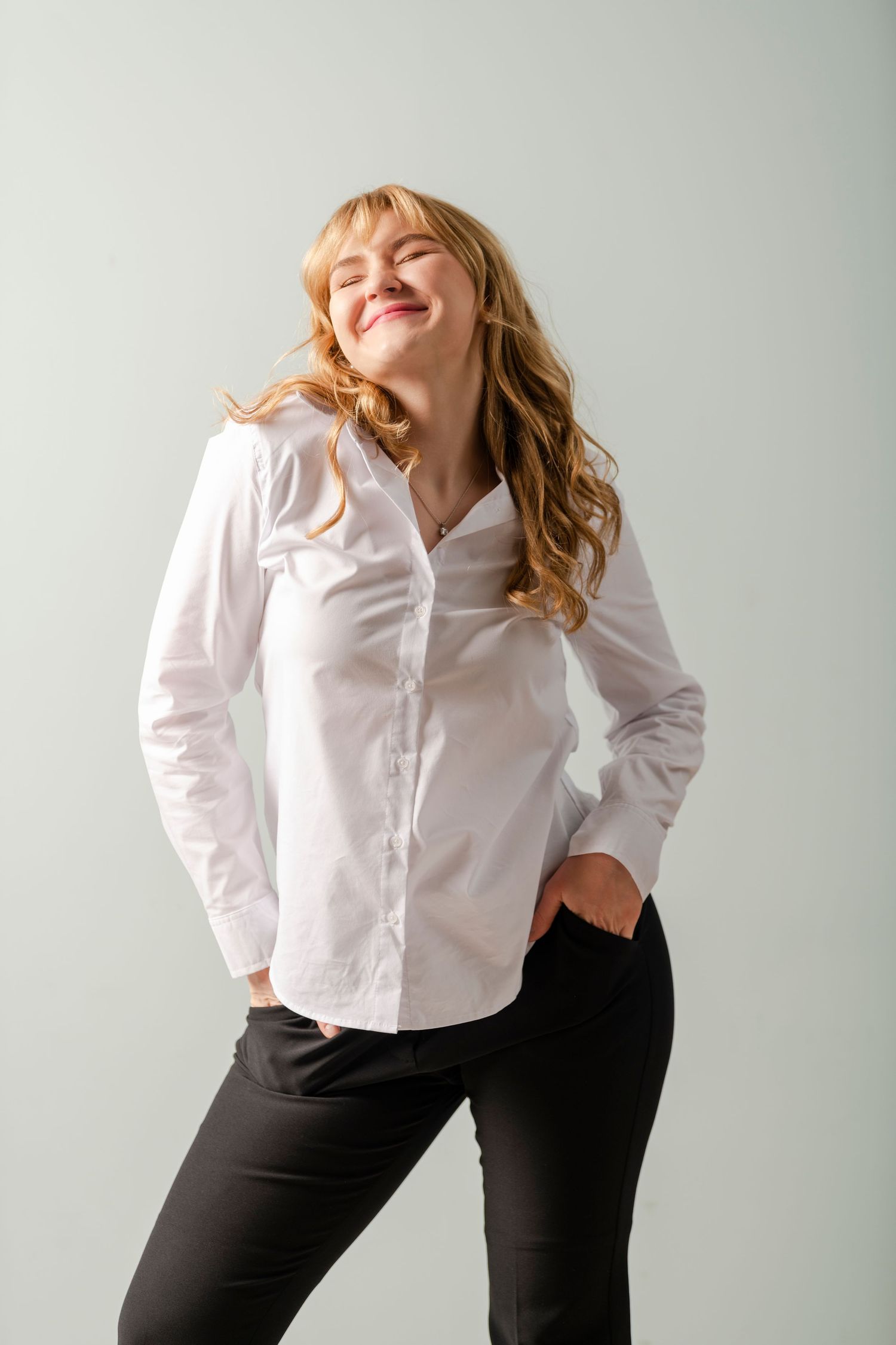 Senior portrait of young woman smiling in studio with soft light and relaxed confident pose