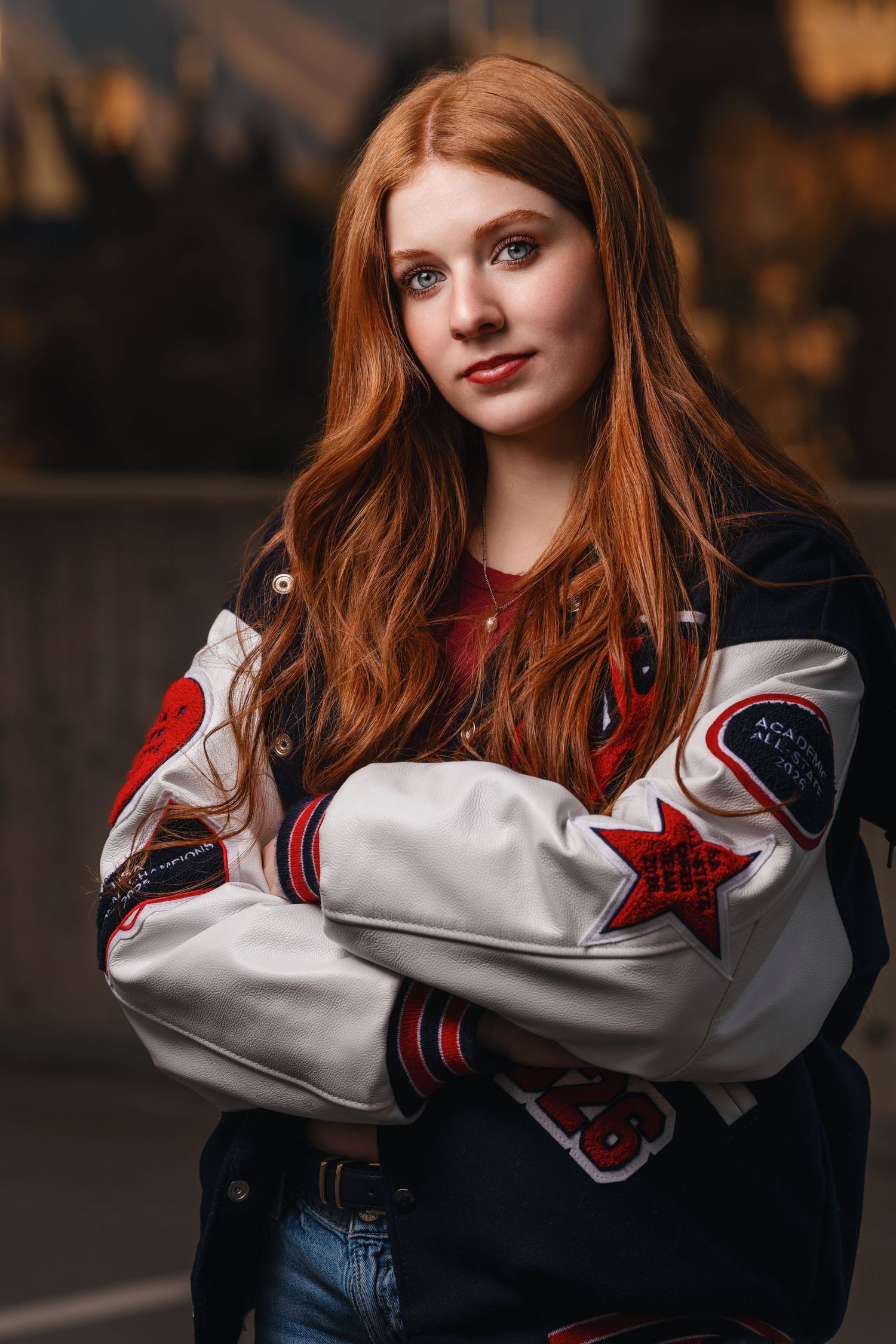 Senior girl portrait wearing letterman jacket with warm tones and confident expression in soft light on a Salt Lake City rooftop