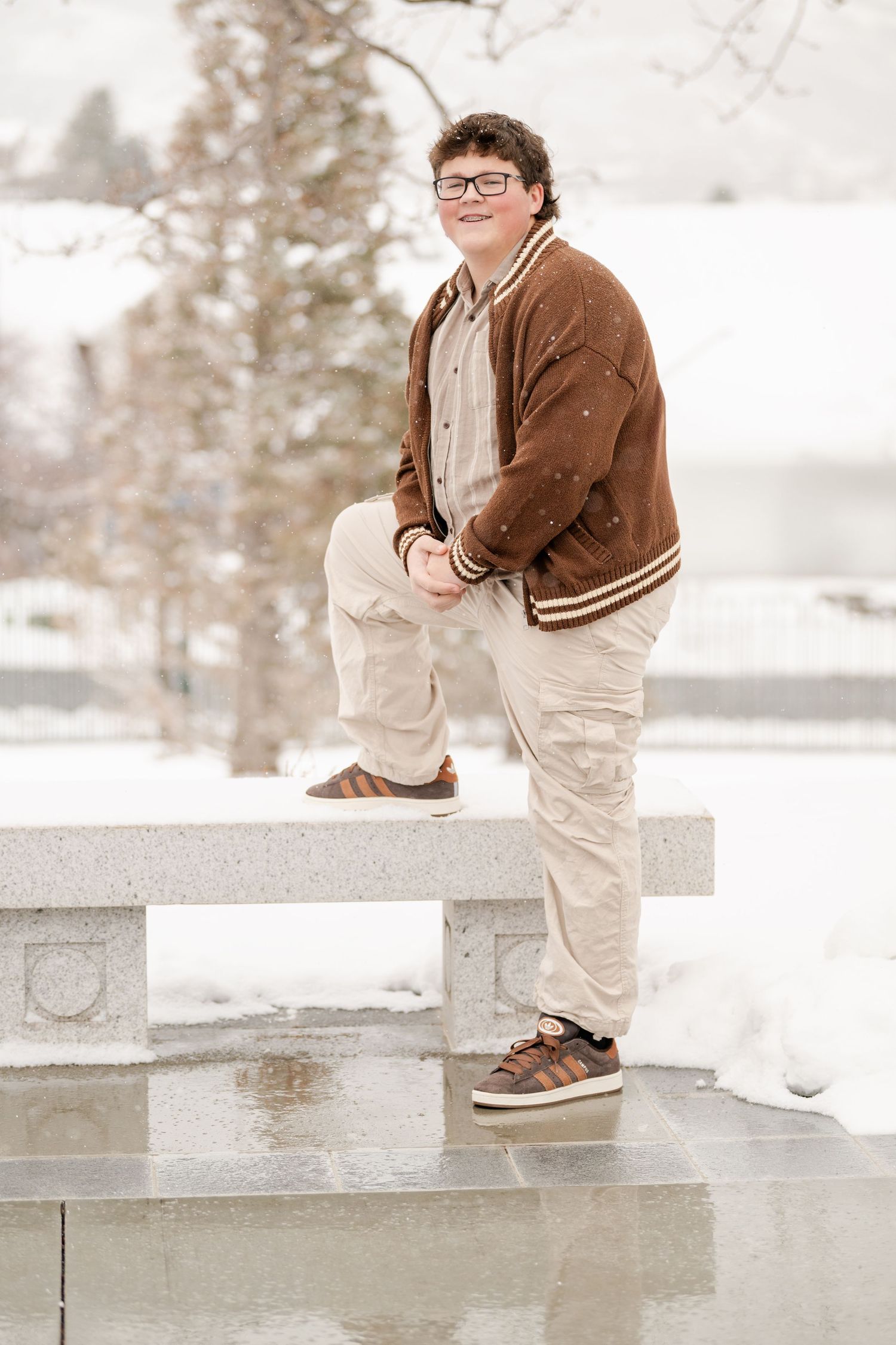 Teenage boy portrait standing on snowy outdoor steps during winter portrait session