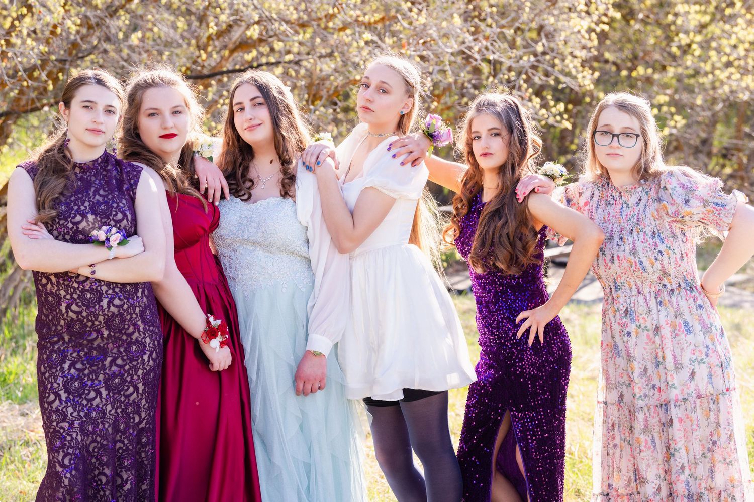 Group of girls in formal dresses posing together outdoors with confident and casual expressions before the Woods Cross Prom dance