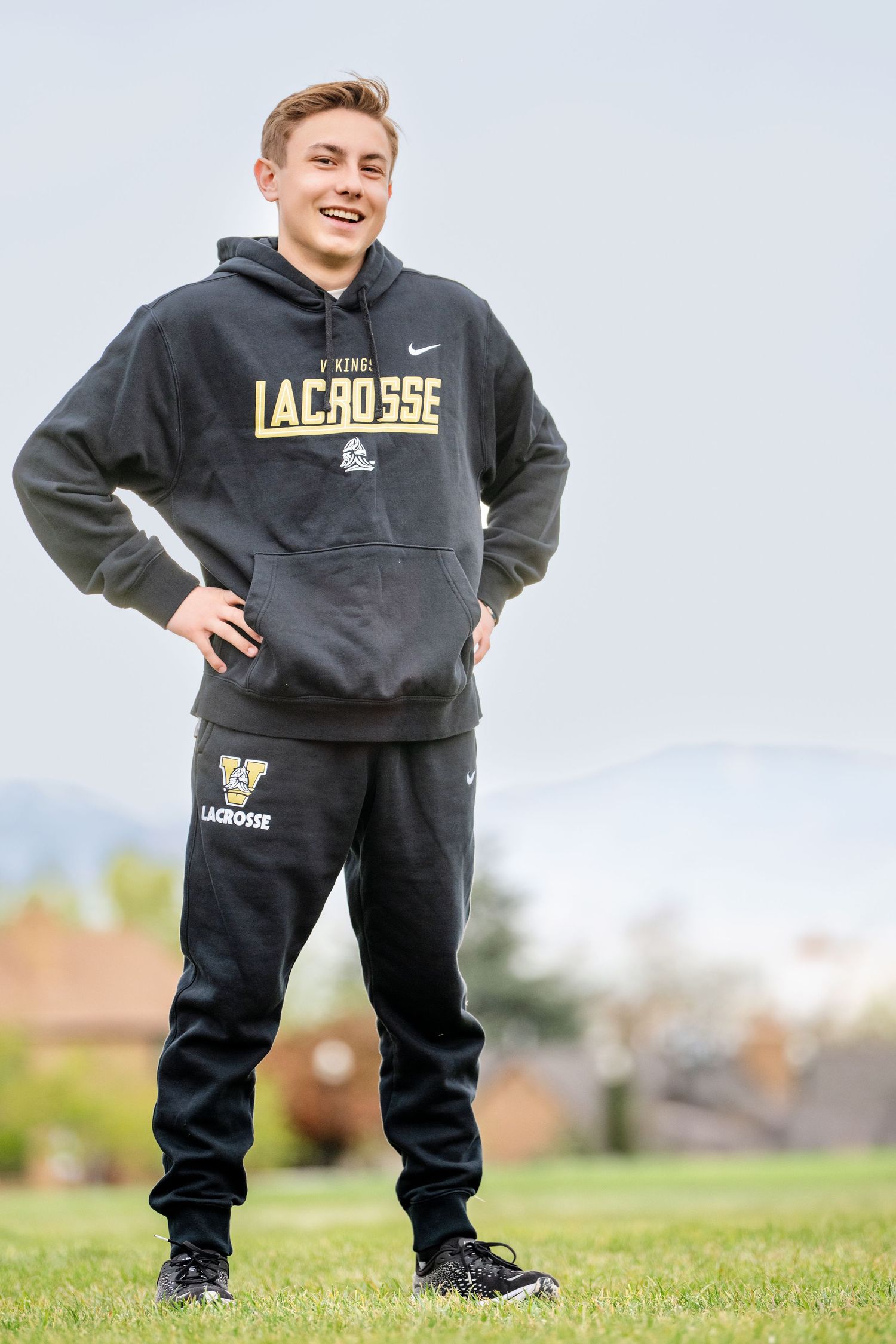 High school lacrosse senior portrait featuring athlete in team warmup gear during outdoor sports session