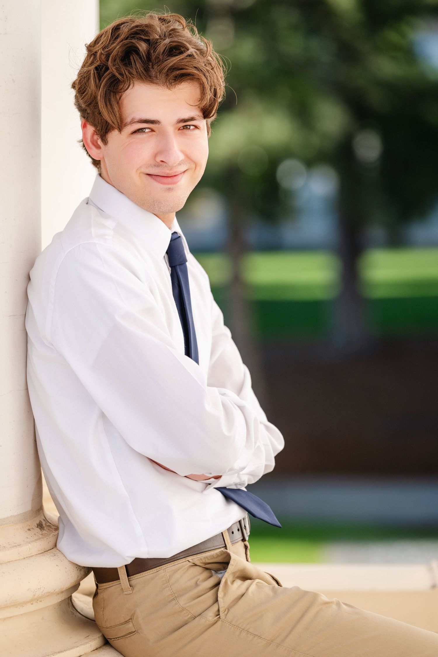 College boy portrait leaning against column wearing white shirt and tie with natural light