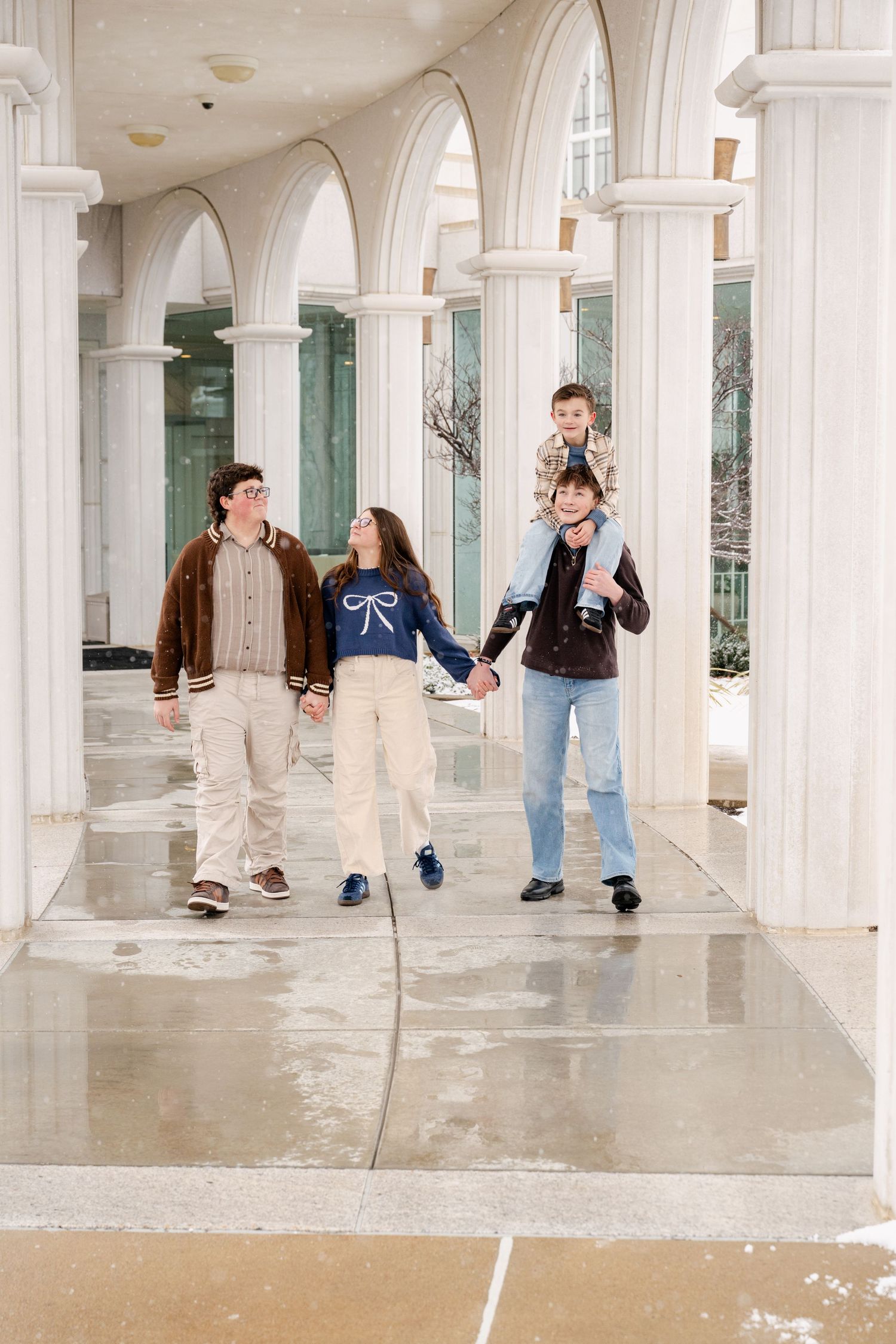 Family walking together through elegant outdoor colonnade during family photography session