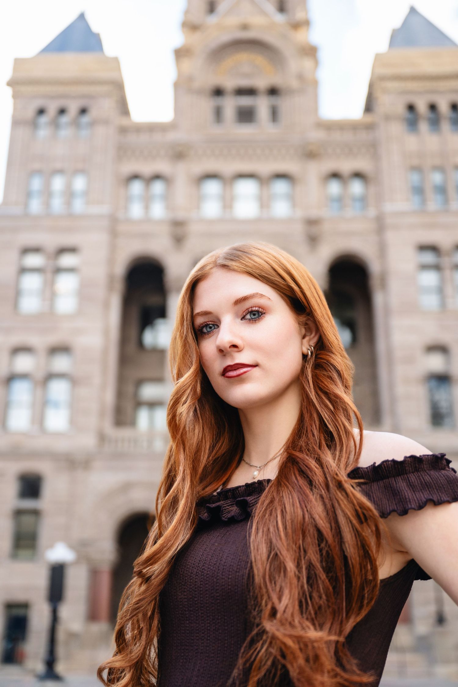 Senior girl portrait in front of historic Salt Lake City building with soft light and confident pose