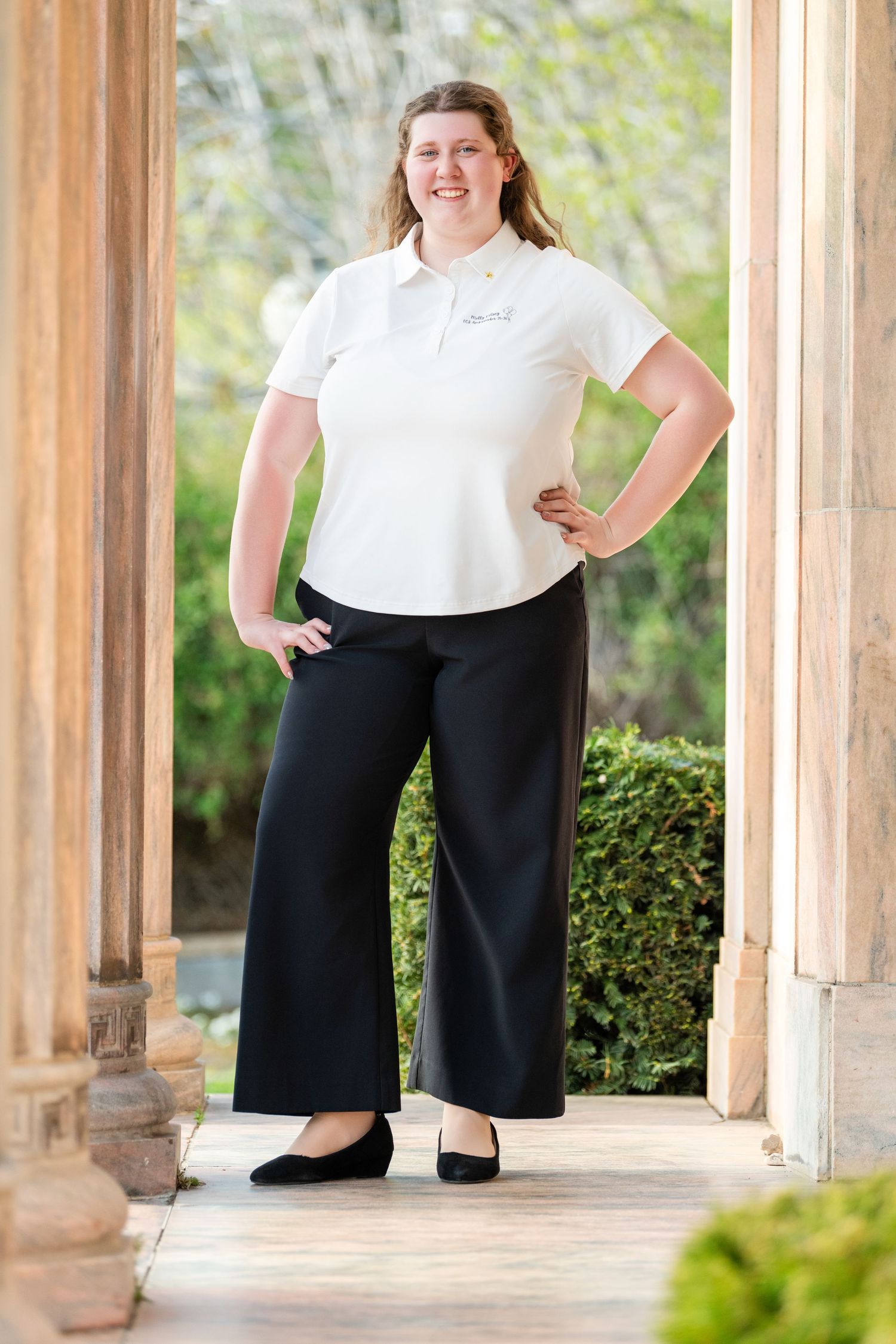 Professional senior portrait of teenage girl standing in elegant outdoor architectural setting