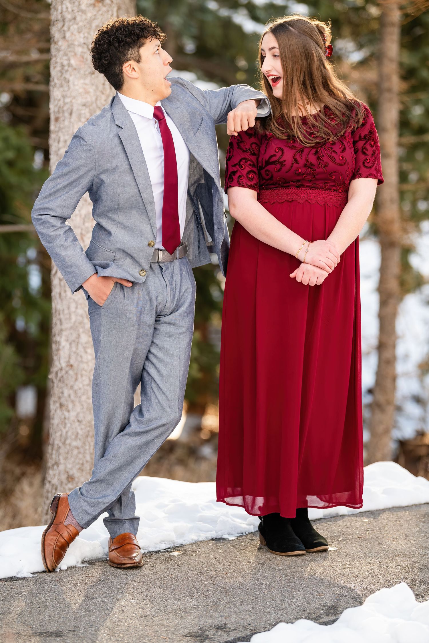 Couple posing together outdoors with red dress and gray suit in soft light