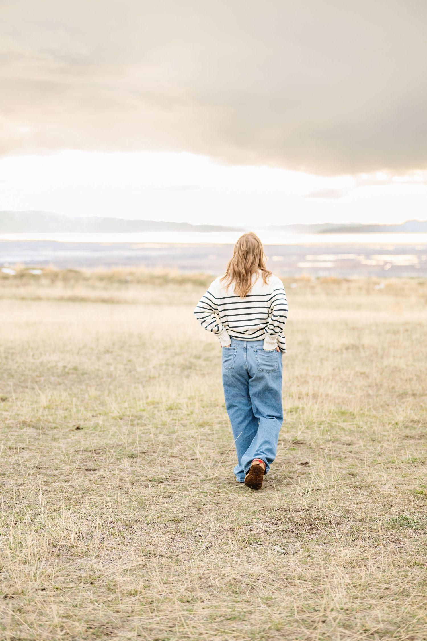 Senior girl walking through open field during natural light outdoor photography session in Utah