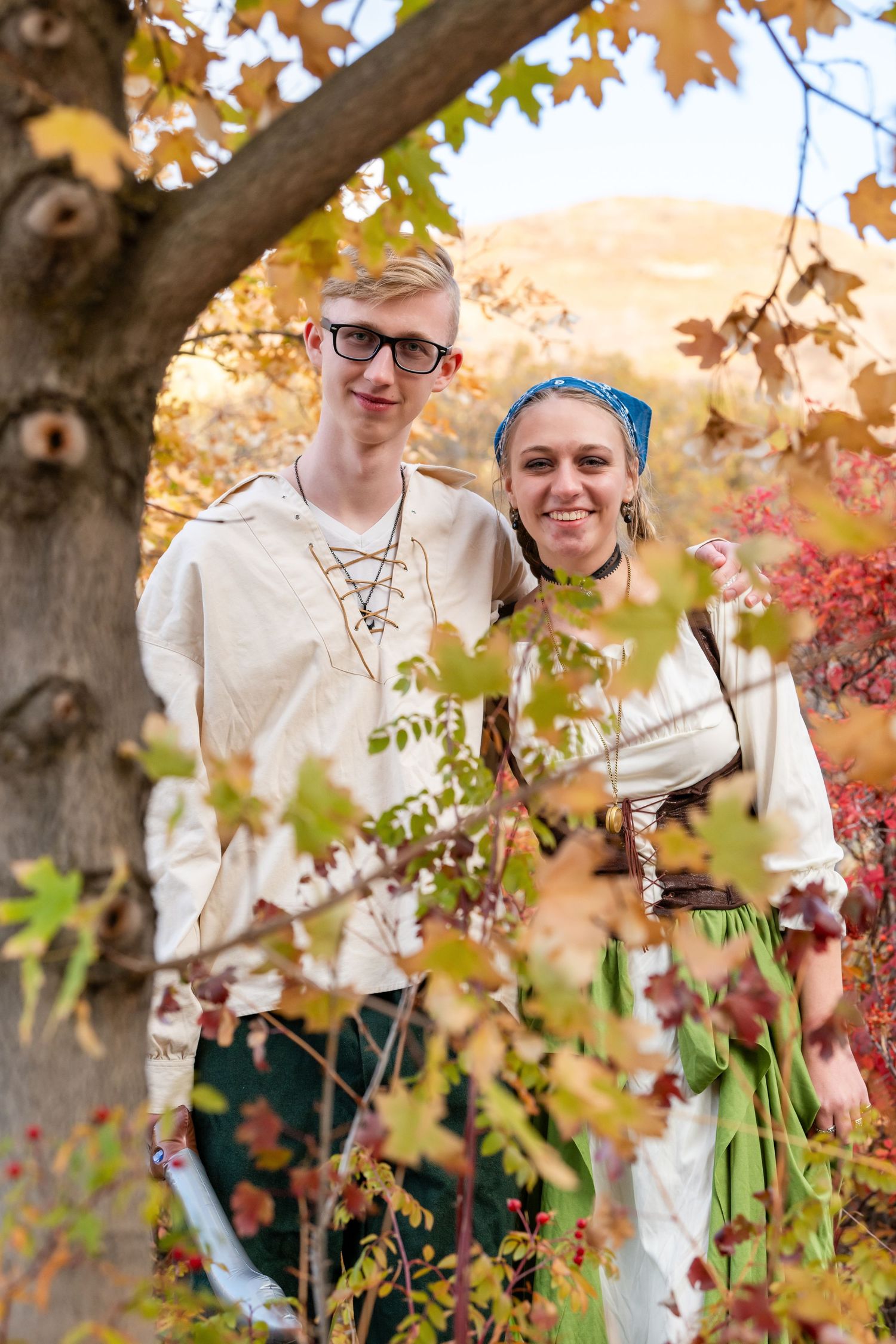 Woods Cross dance couple standing under tree with fall leaves in pirate themed outfits smiling together