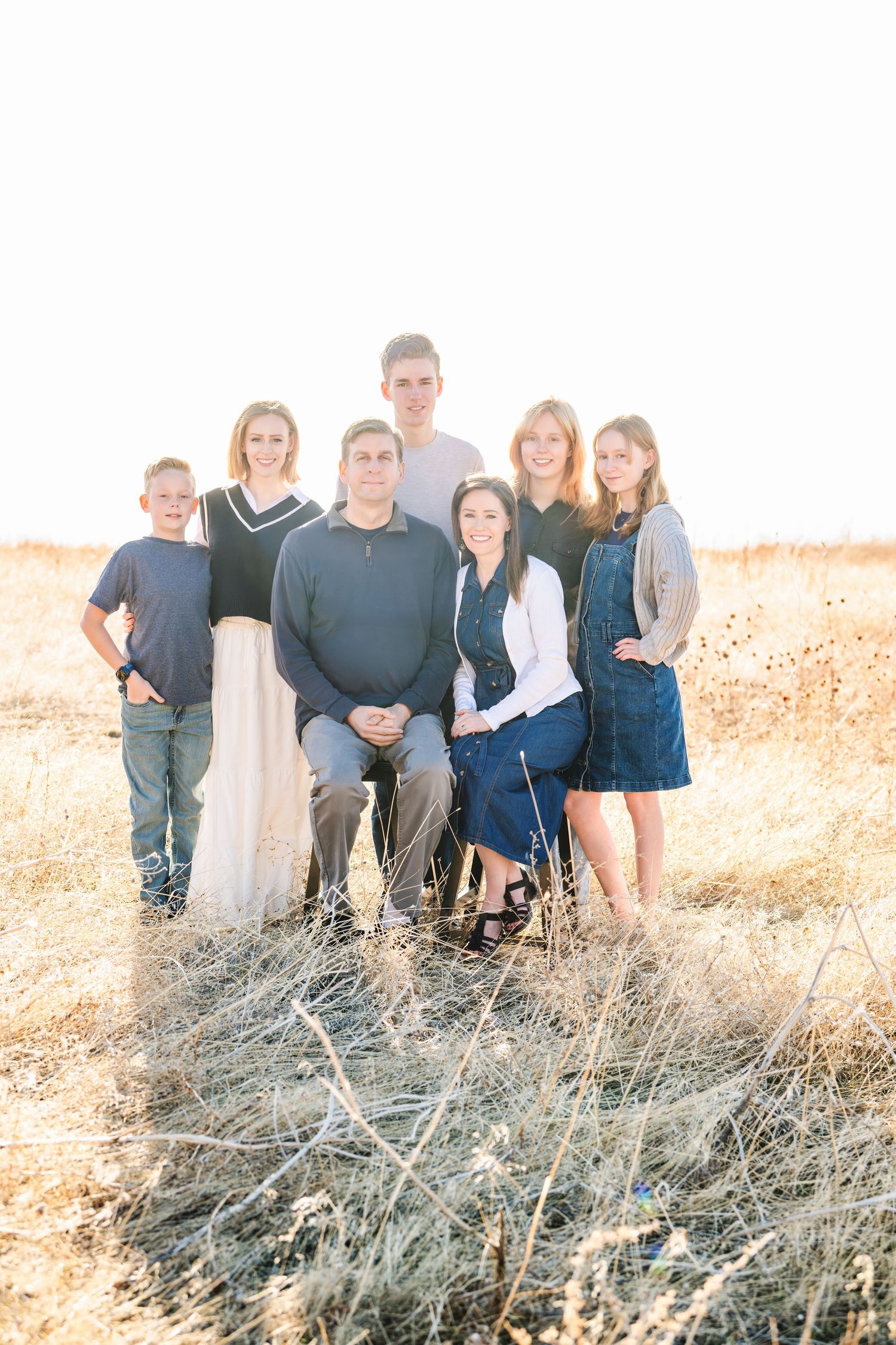 Outdoor family portrait standing together in tall grass during golden hour photography session