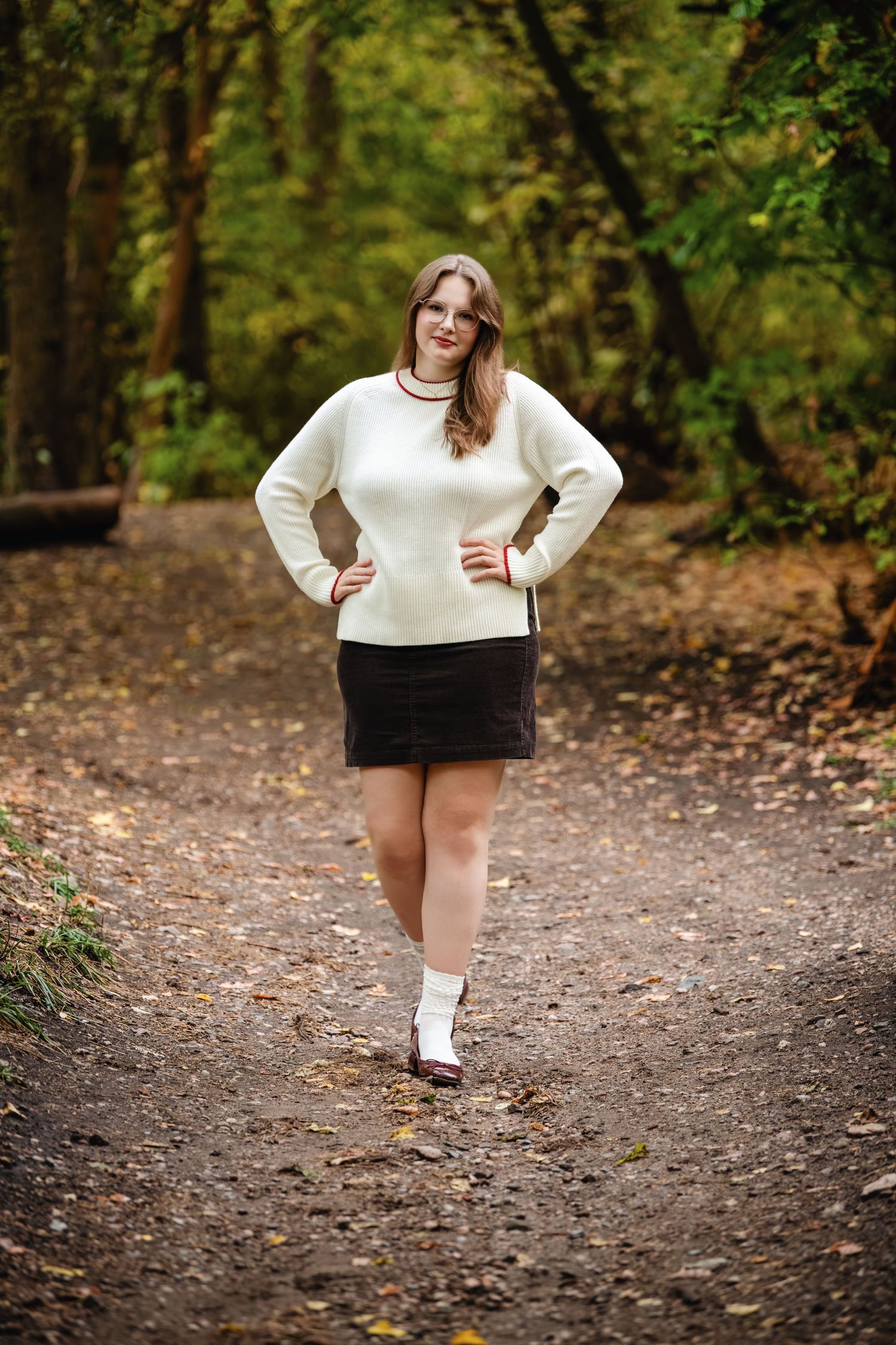 Senior girl walking Mueller Park Canyon forest path wearing sweater and skirt with natural green background