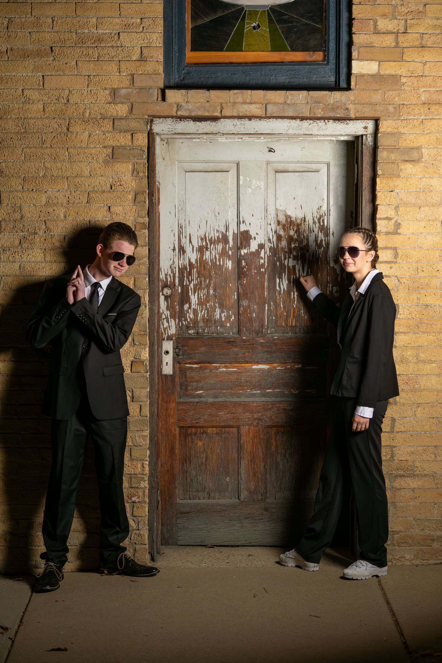 Fun WXHS Sadie Hawkins dance photos with students dressed in black suits and sunglasses near vintage doorway
