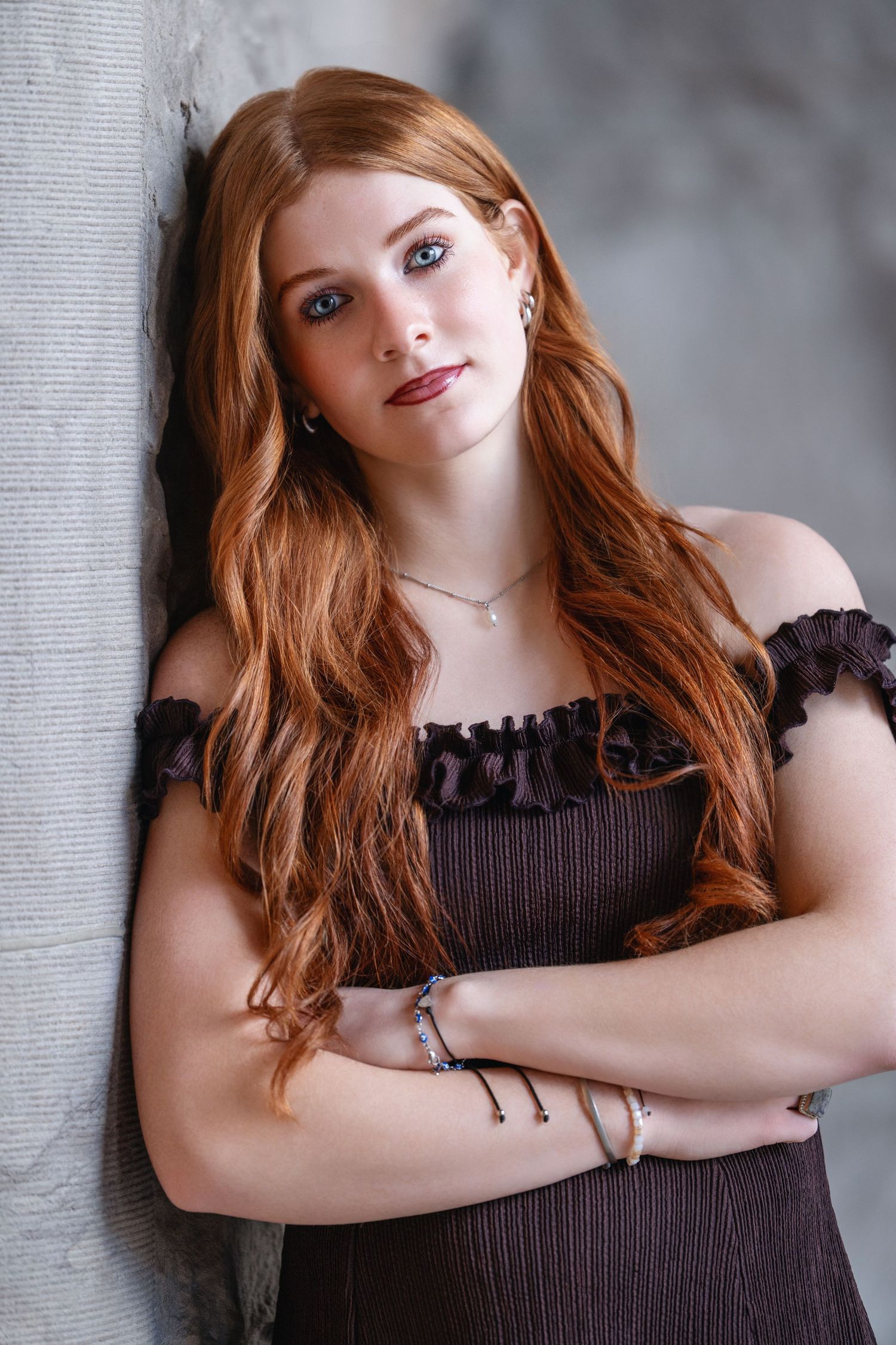 Senior girl leaning against wall with soft natural light and relaxed natural expression