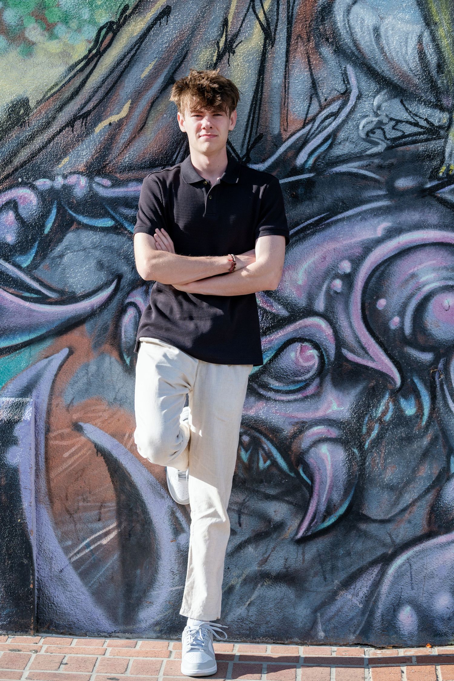 Senior boy portrait standing against graffiti wall in urban Salt Lake City setting with casual pose and modern style