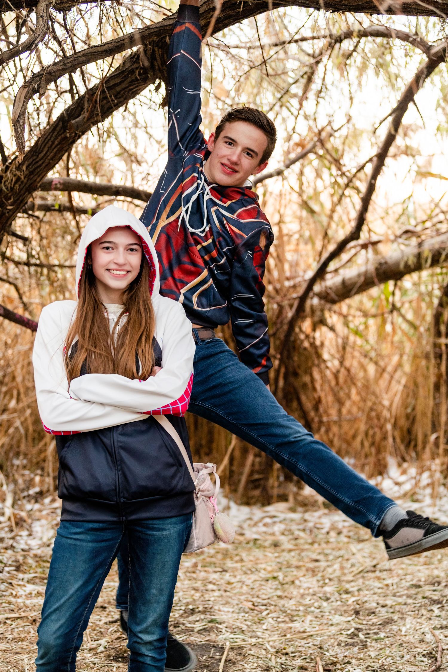 Two teens posing by tree in Spider Man themed outfits with playful pose in natural setting for Woods Cross Sadie Hawkins dance