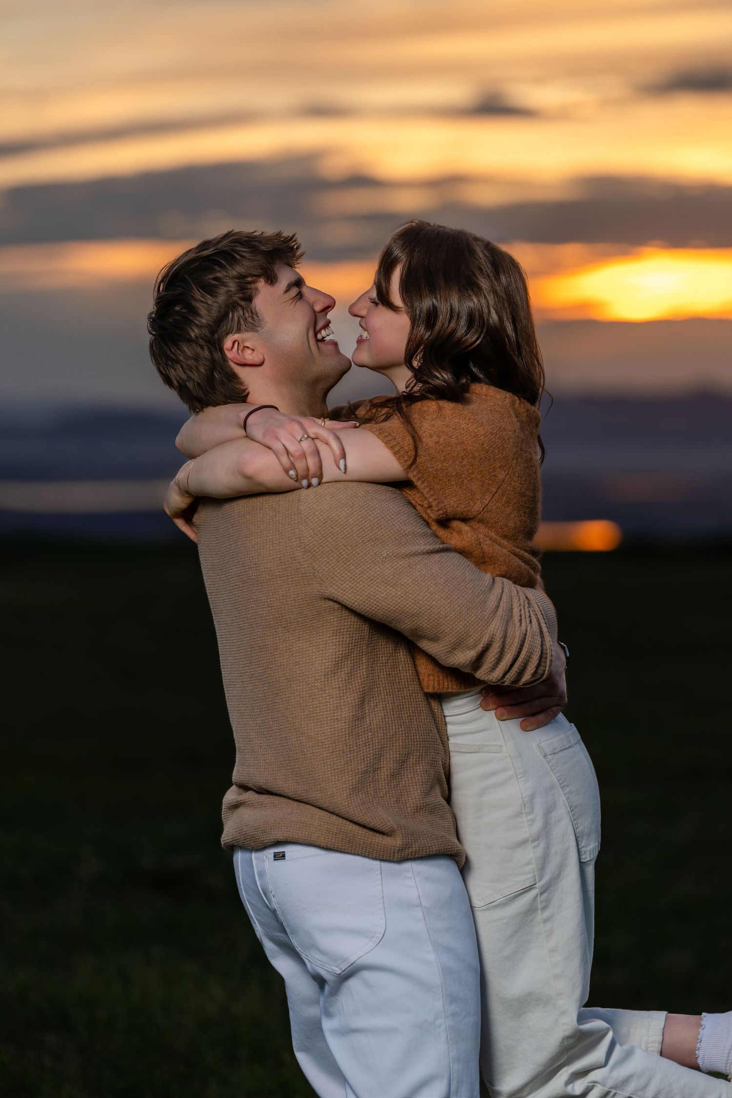 Golden hour engagement portrait of couple hugging outdoors during Utah sunset photography session