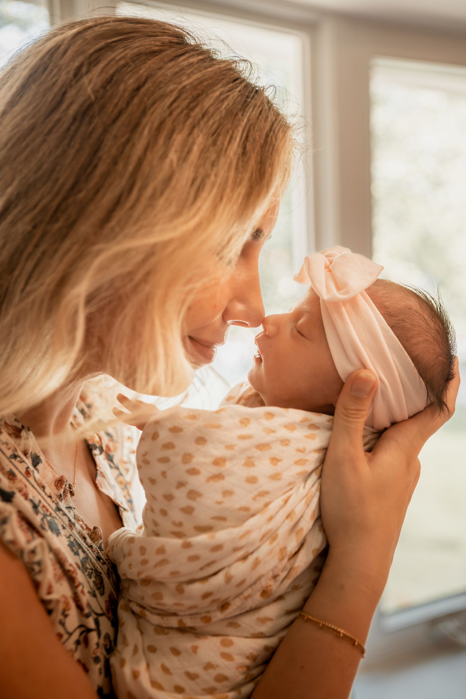 A parent tenderly holds and comforts a small baby near a sunlit window in a gentle nurturing moment.