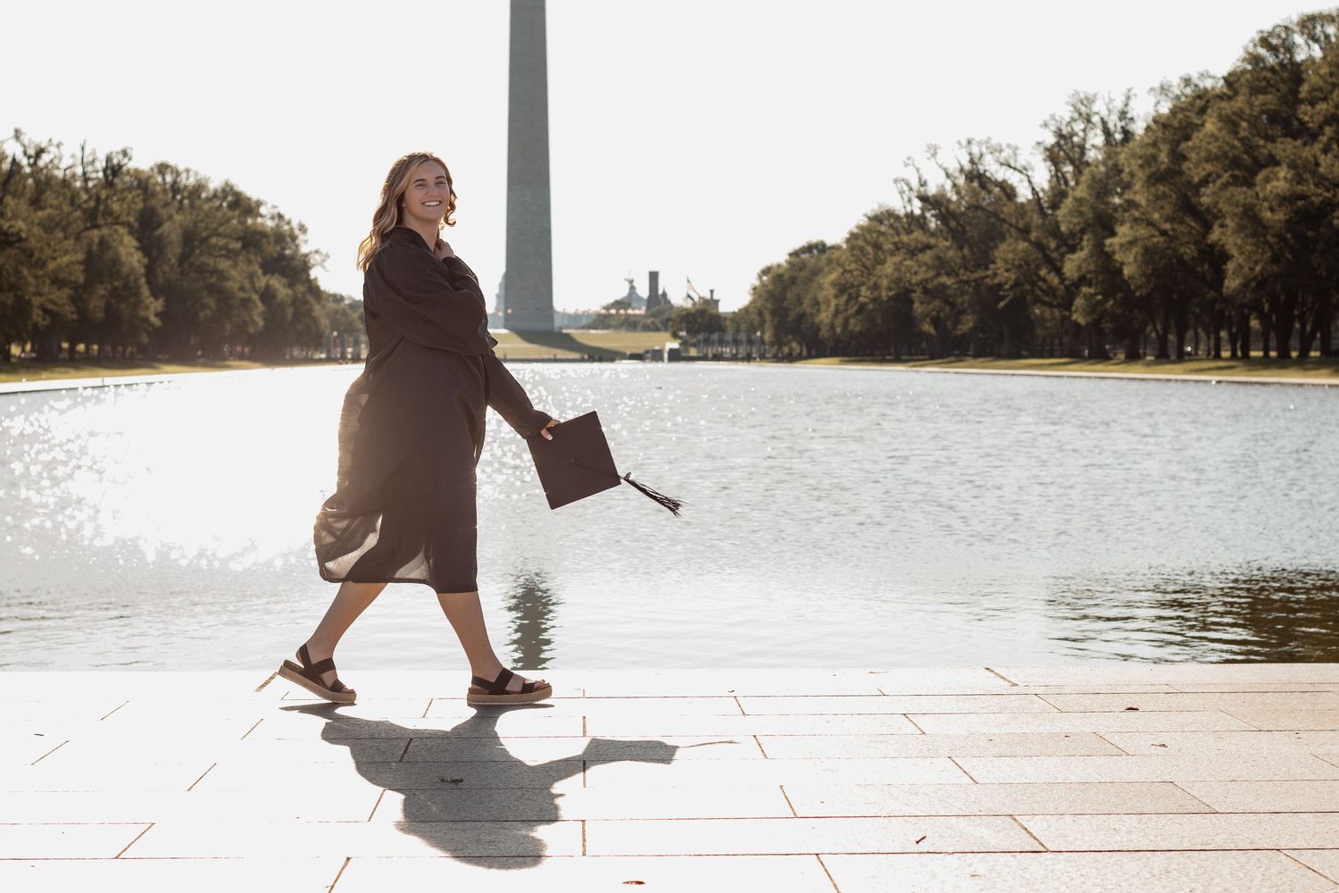 Person stretches on a lakefront path during a bright sunny morning as the Washington Monument stands in the background.