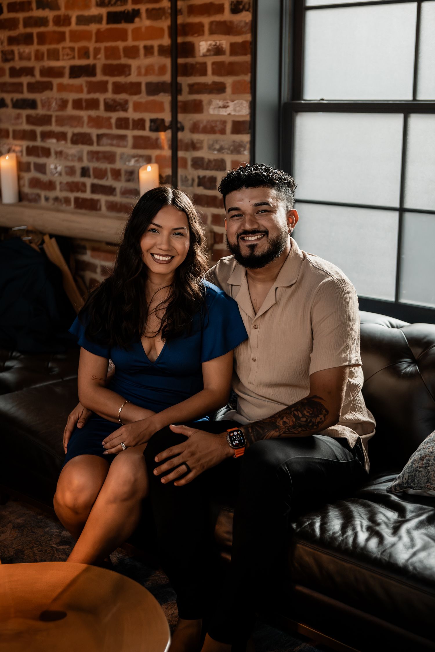A couple sharing a relaxed moment on a leather couch in an industrial-style space.