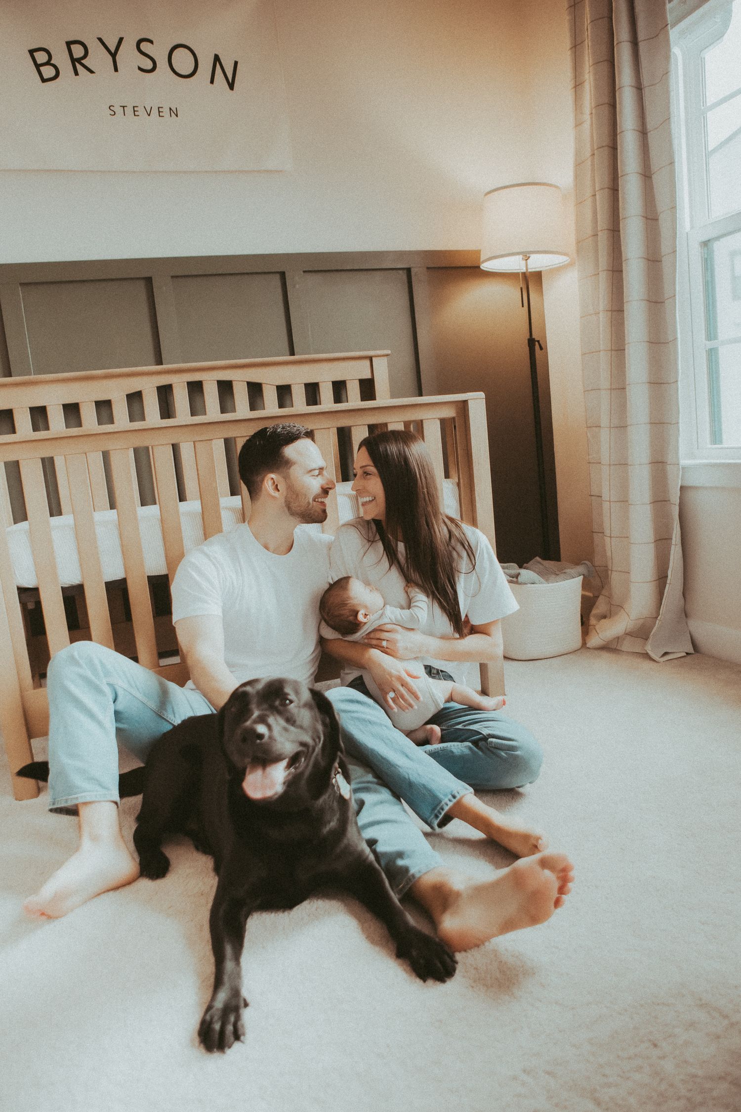 Family relaxing together on bed with dog in cozy bedroom setting.