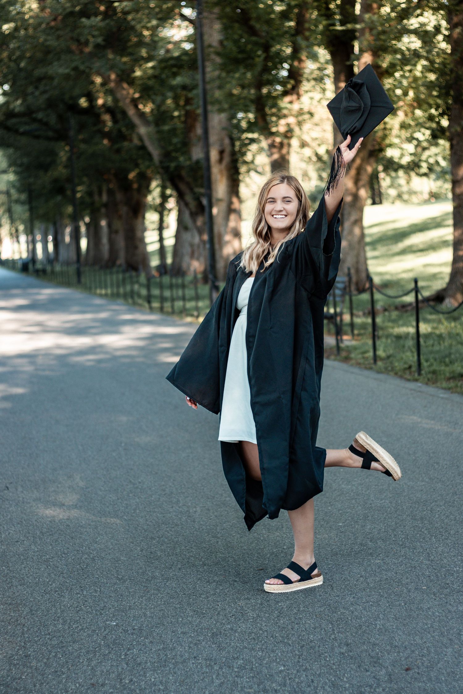 Someone wearing a graduation gown standing on a path does playful dance movements in a series of photos.
