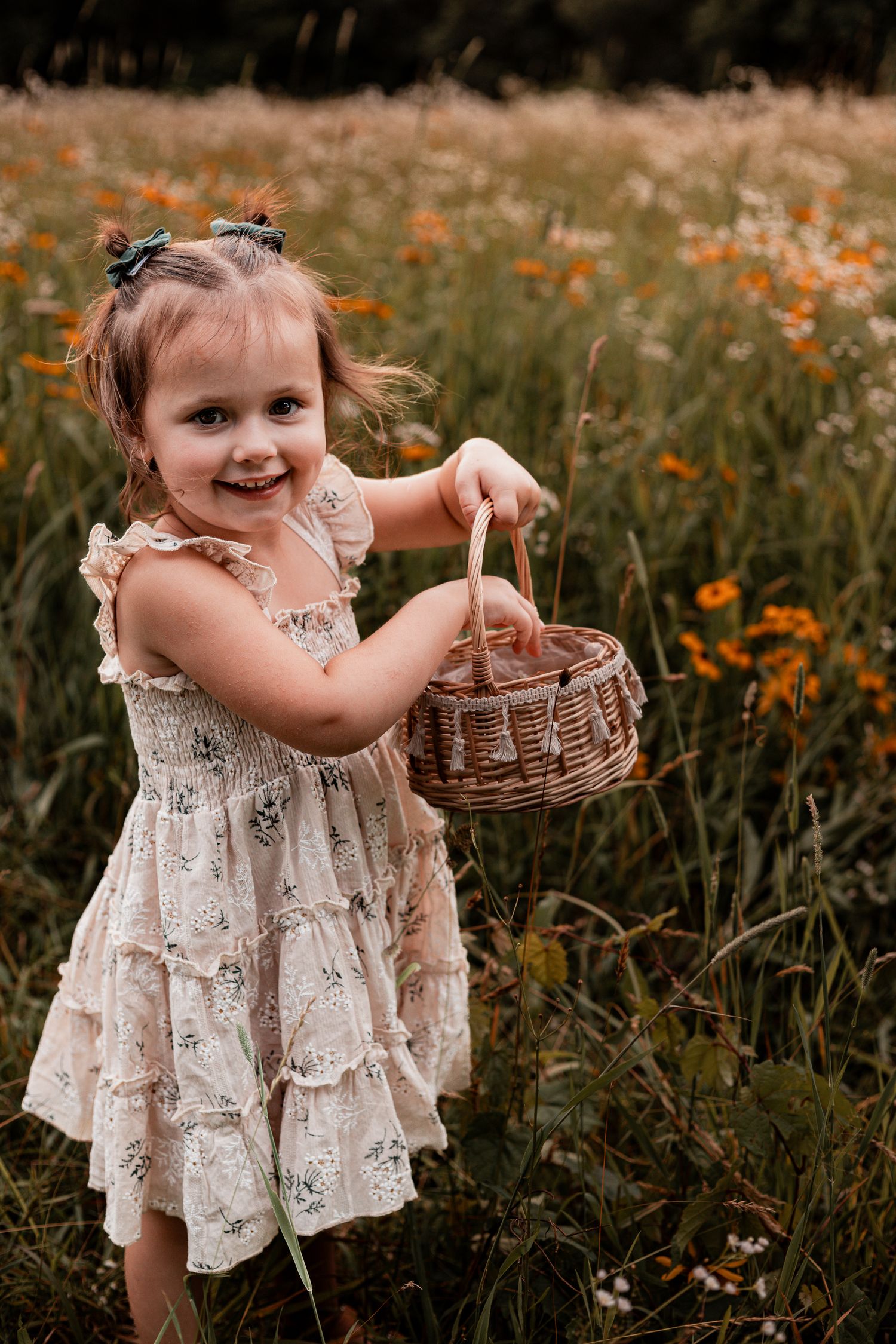 Child in a lace dress explores a flower field while carrying a small woven basket.