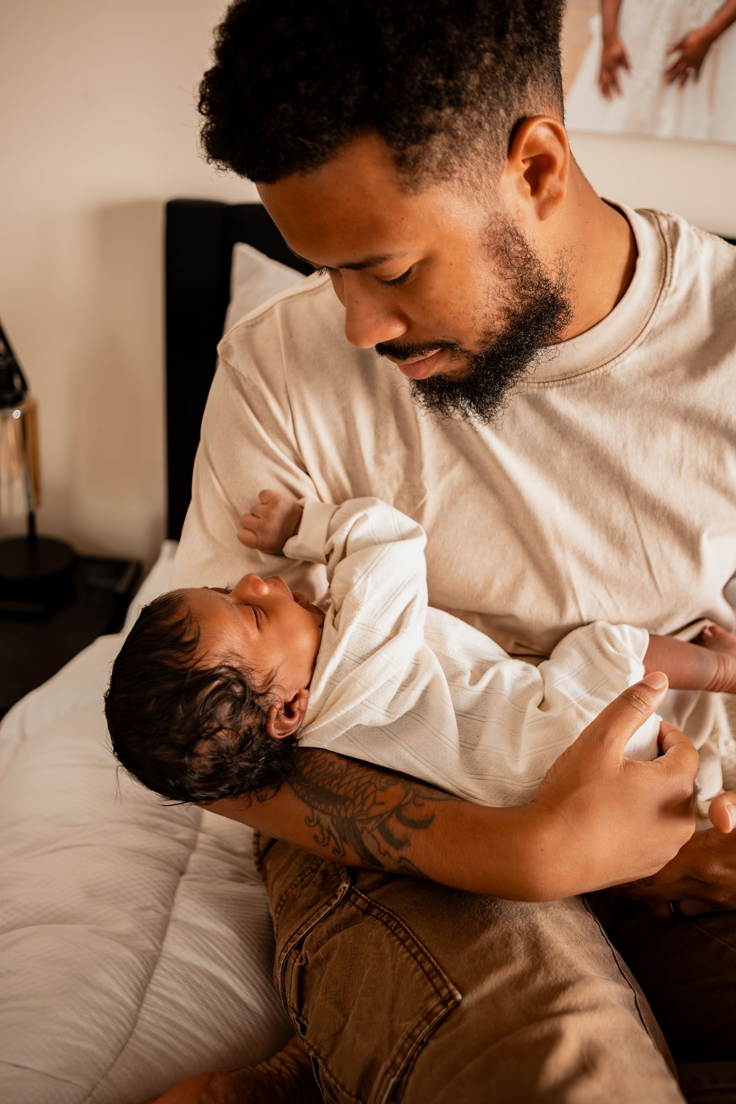 A series of intimate bonding moments between parent and baby lying on white bedding in warm lighting.