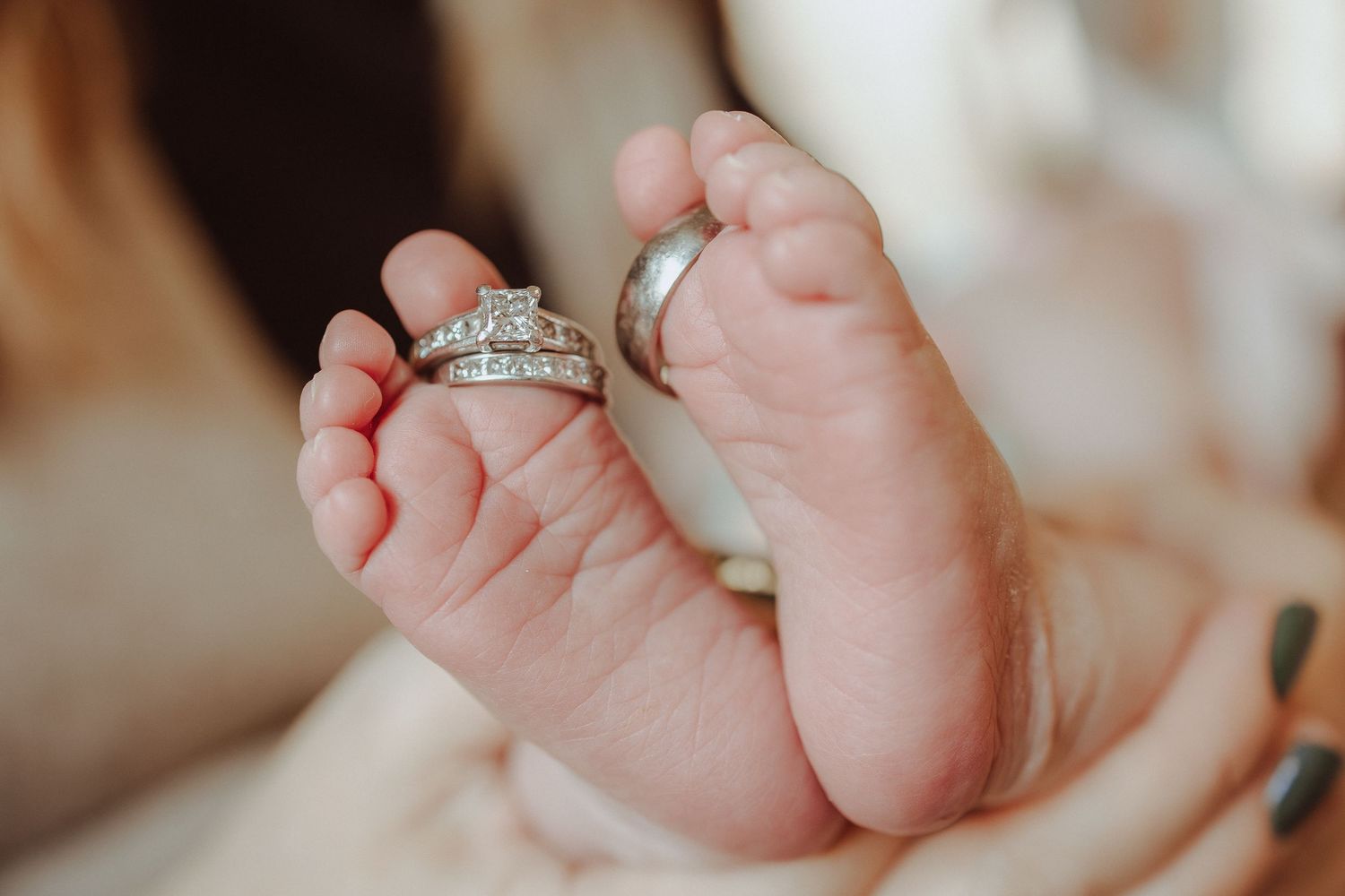 Close-up view of a newborn baby's tiny feet being gently held by adult hands.