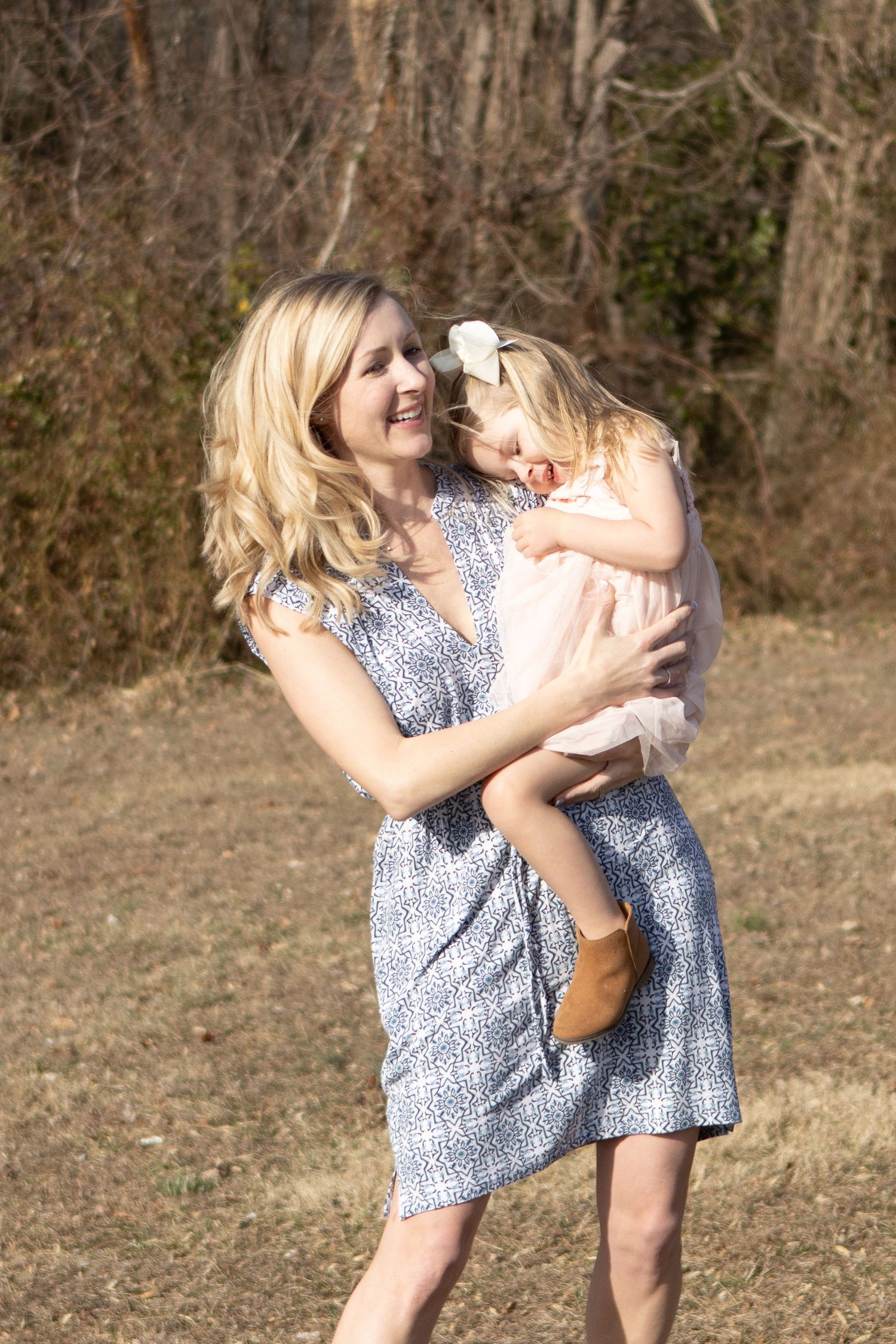 Two children in blue floral dresses playing together outdoors on a sunny day.