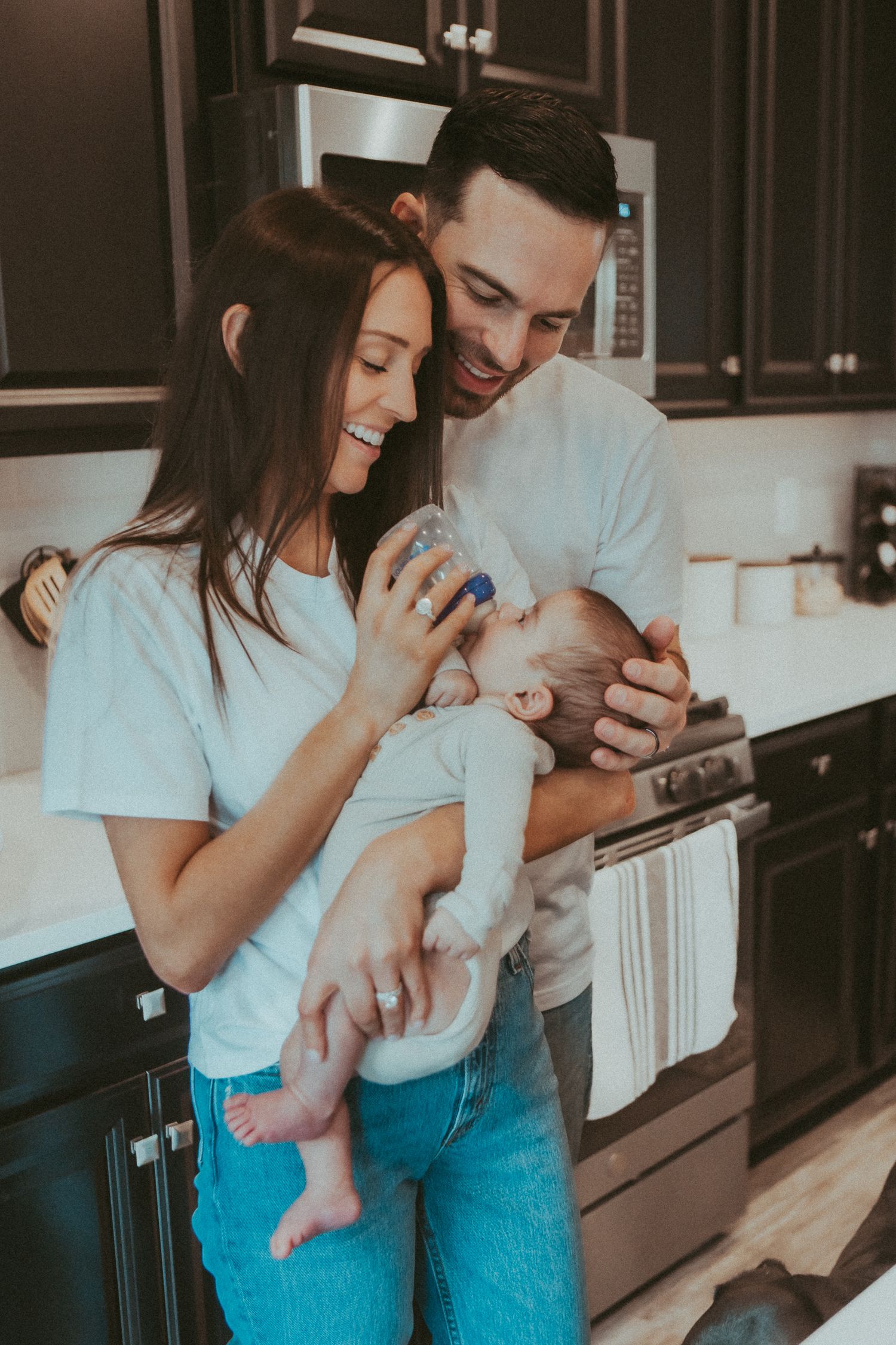 Candid family moment in kitchen showing playful interaction with baby.