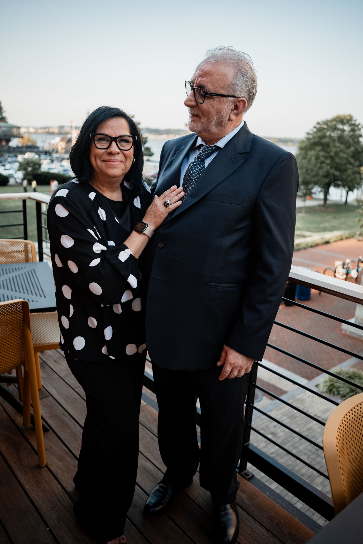 Couple in formal wear posing on outdoor deck with polka dot dress and suit.