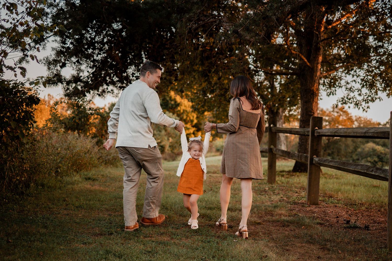 Family walking together in a park at sunset holding hands and baskets during golden hour.