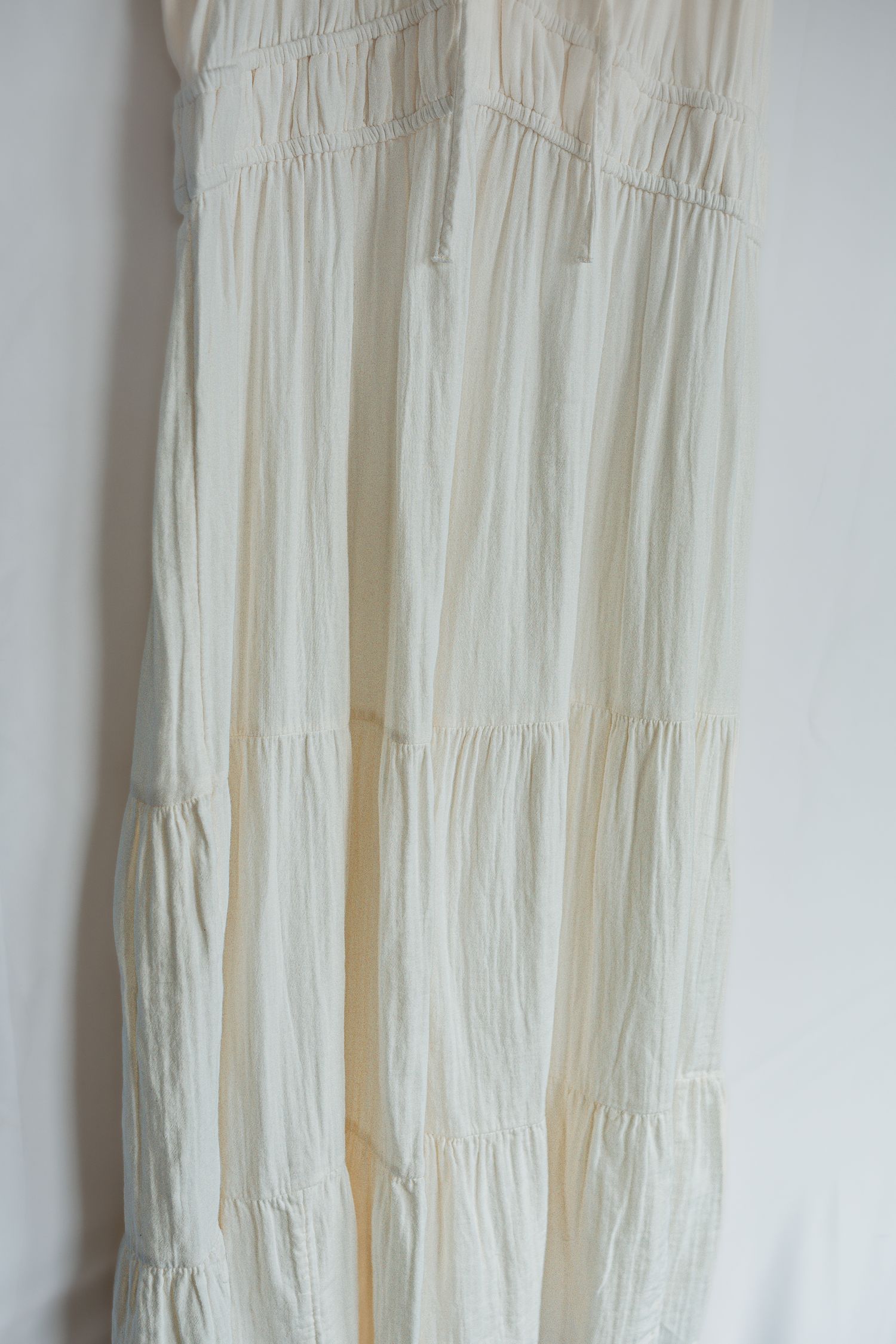 Vintage white hand-smocked cotton dress with intricate pleating details displayed against a light colored wall.