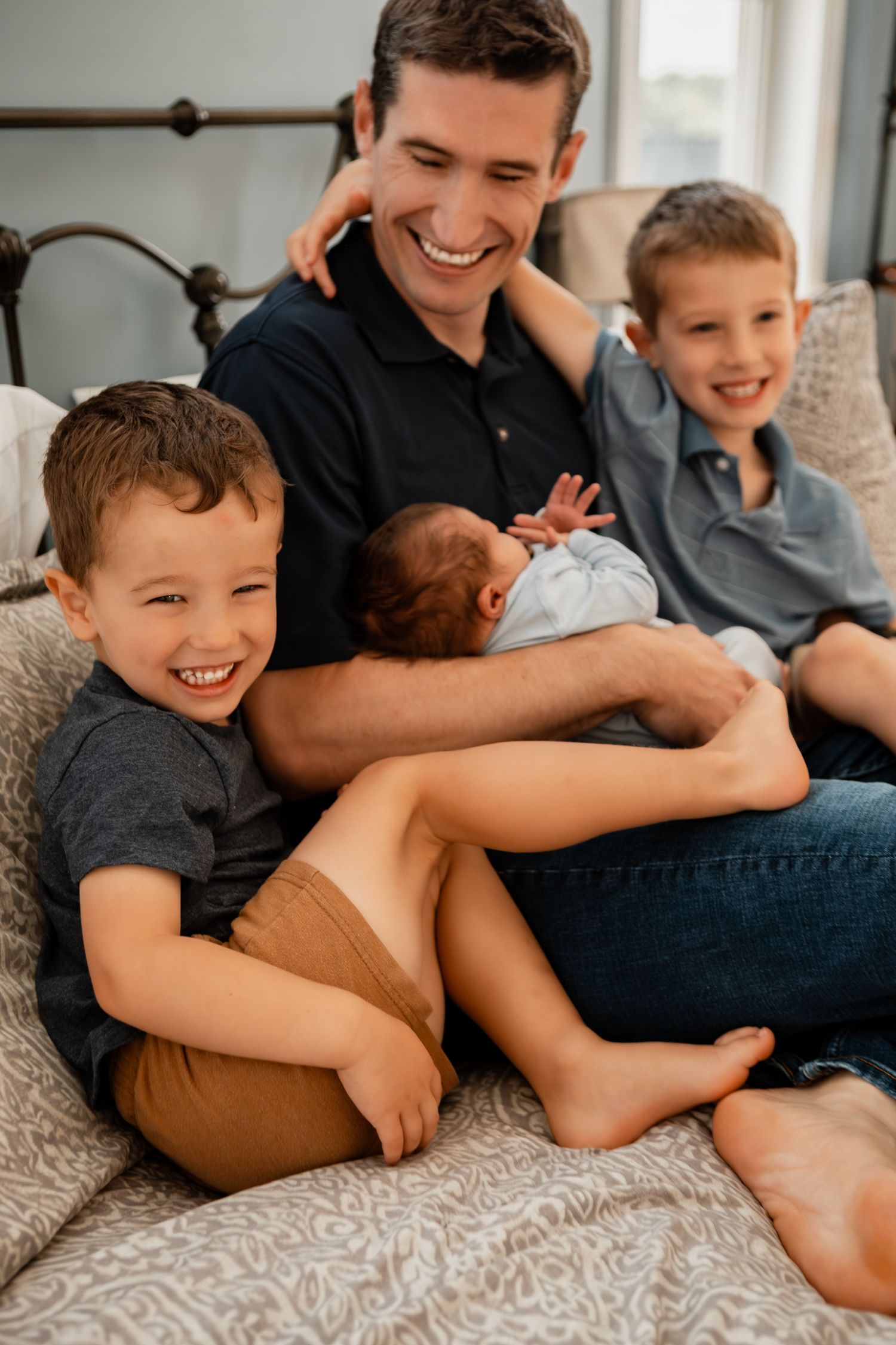Family enjoying playful cuddles and laughter while lounging together on comfortable bedding.