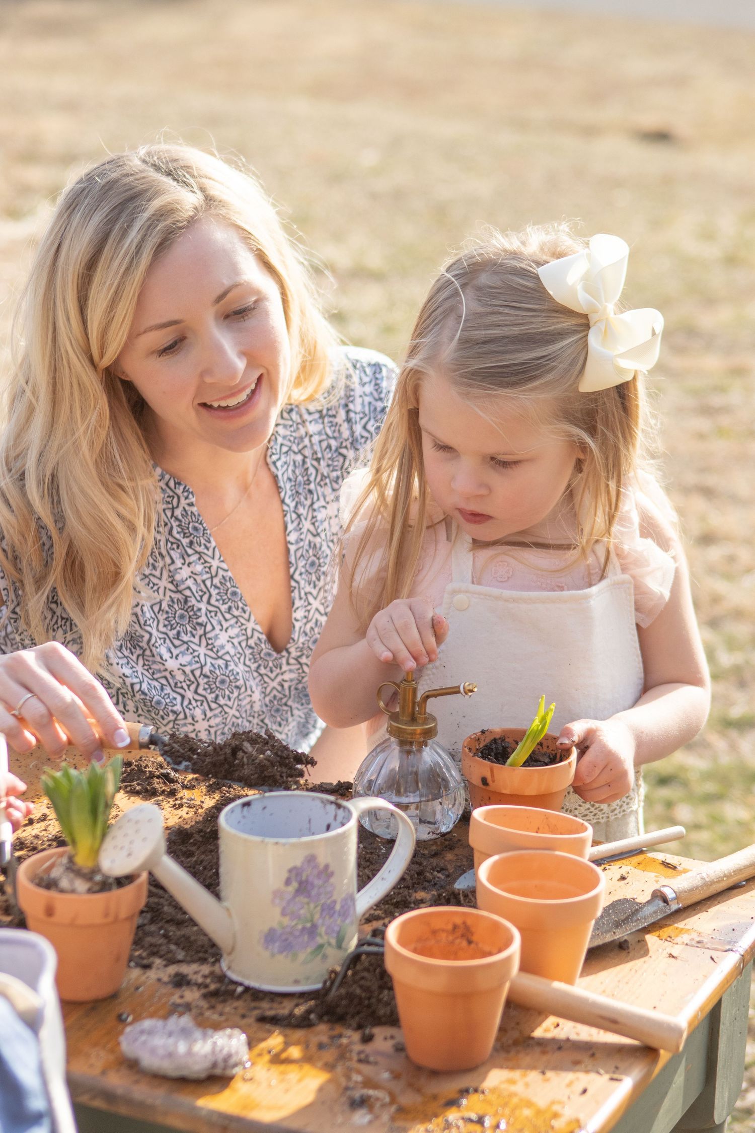 Spring gardening scene with teapot and terracotta pots on outdoor table.