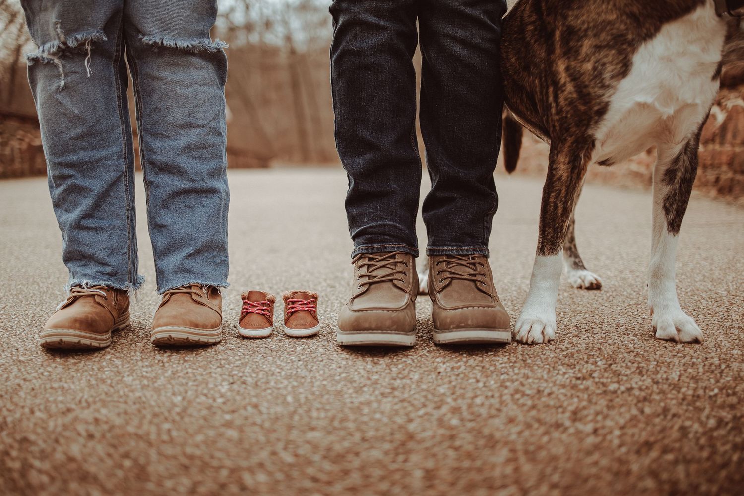 Row of people's feet and legs standing together with a dog visible at ground level in a sepia-toned photograph.